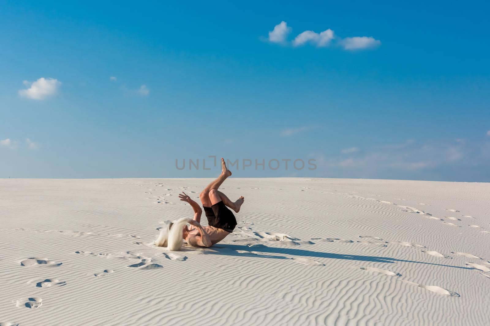 Young sporty man want doing acrobatic exercises on the sand near river. Portrait of young parkour man