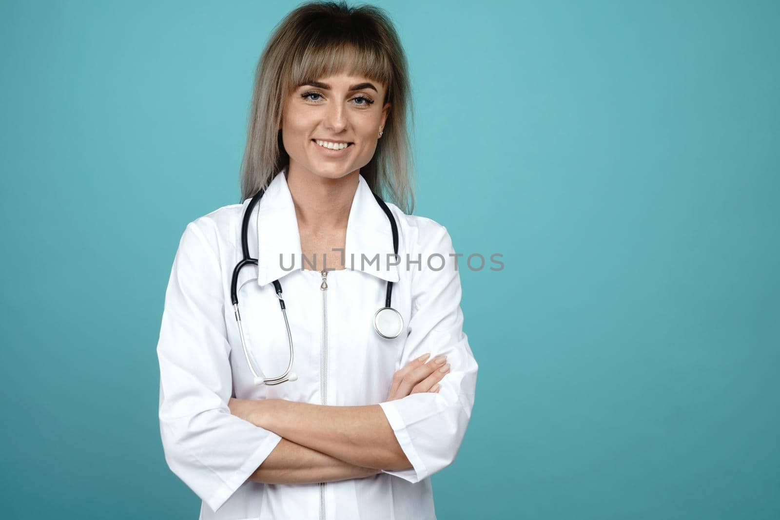Smiling young female doctor with a stethoscope standing on a blue background