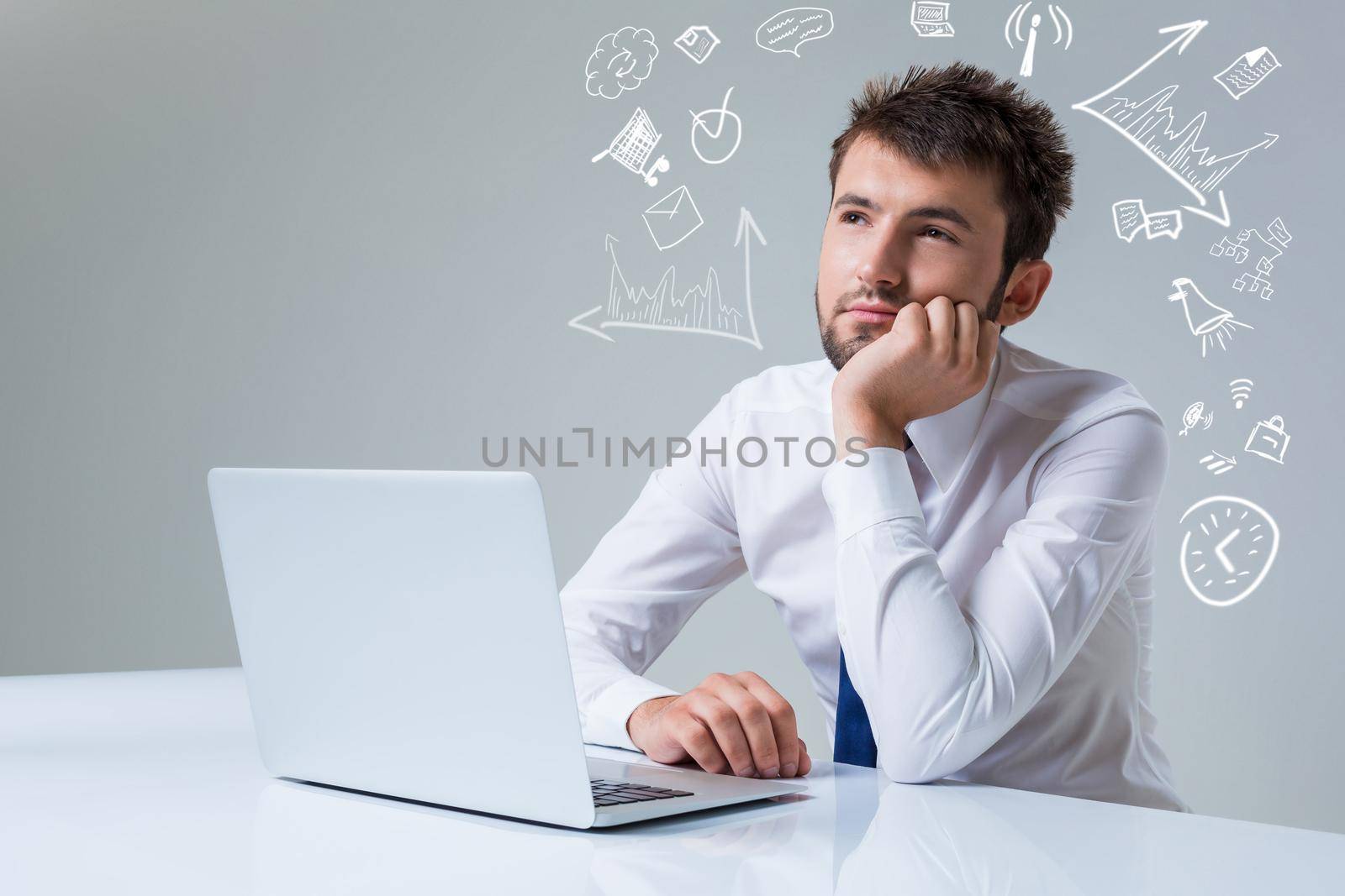 young man thinking uses a laptop computer while sitting at a table. Office clothing