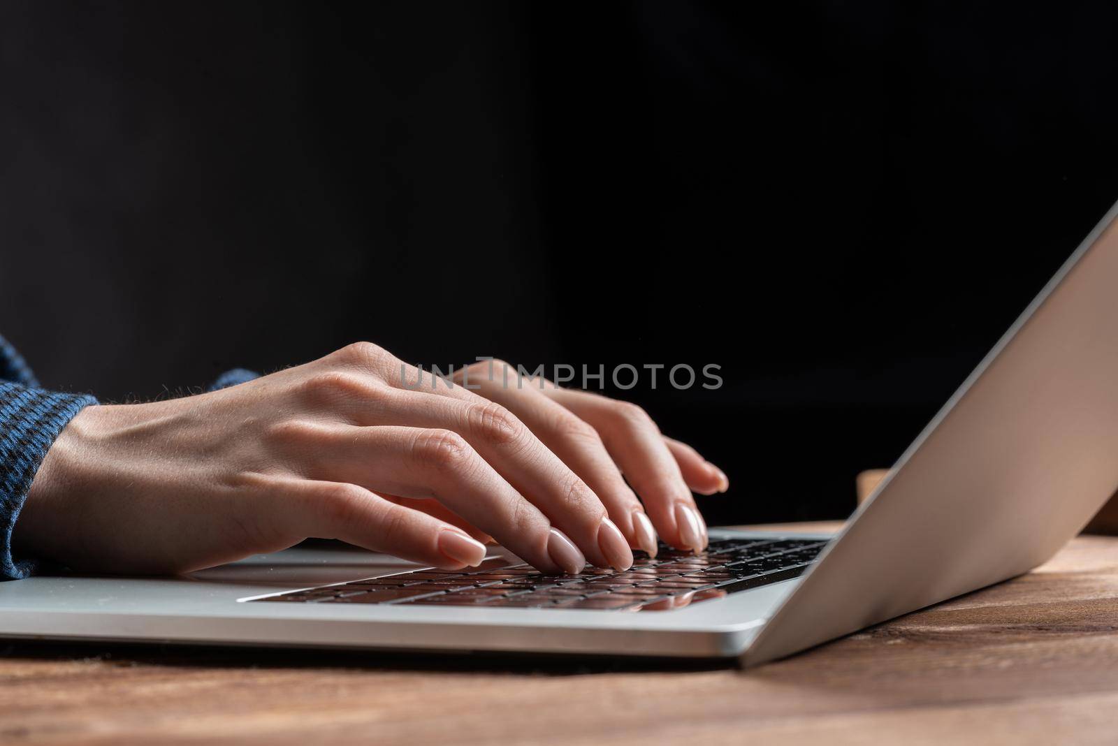 Close up woman hands lying on laptop keyboard. Business lady working with computer at wooden desk. Financial specialist working at workplace in office. Business accounting and project management.