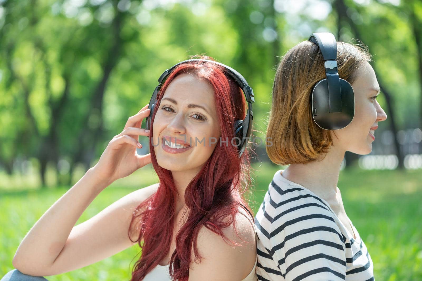 Two young girls in the park listen to music. by adam121