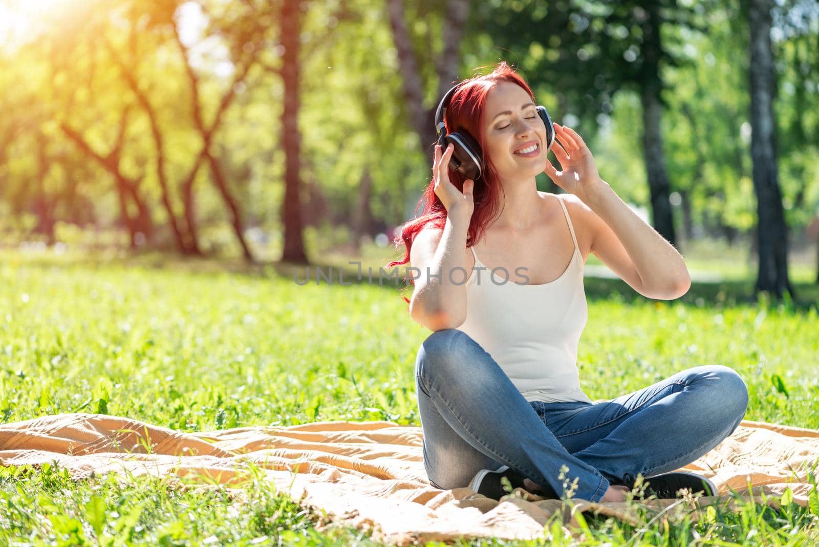 Young attractive woman listens to music in the park. Enjoying music in the park