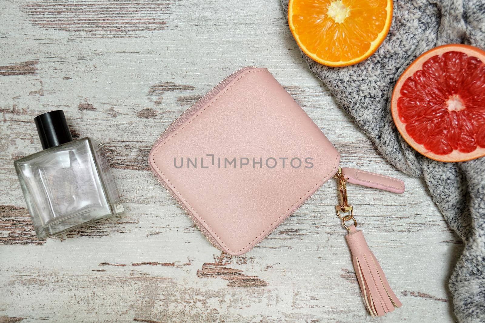 Little pink female purse, perfume and citrus on a wooden background. Fashionable concept.
