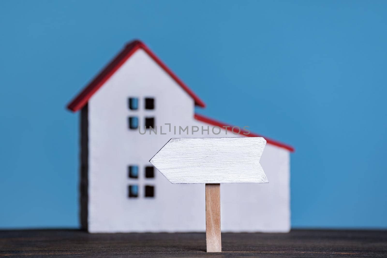 Wooden signboard on house background. Own accommodation concept. Blue background, front view.