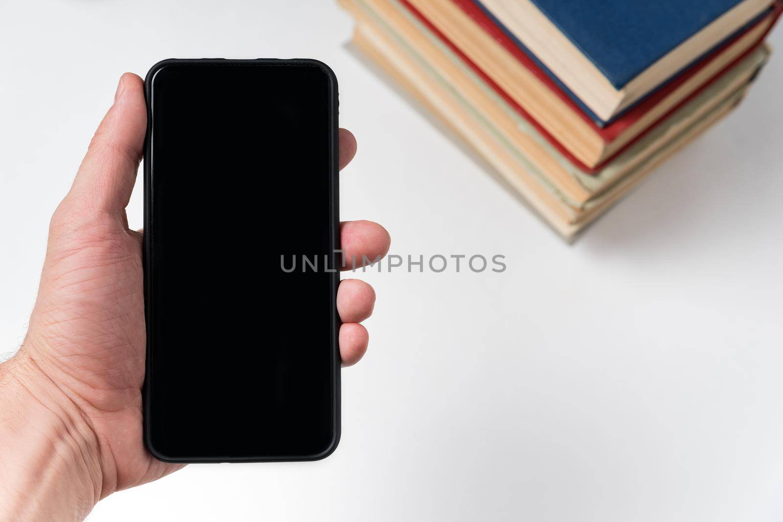 Mobile phone in hand on the background of books. E-book concept. White background, copy space.