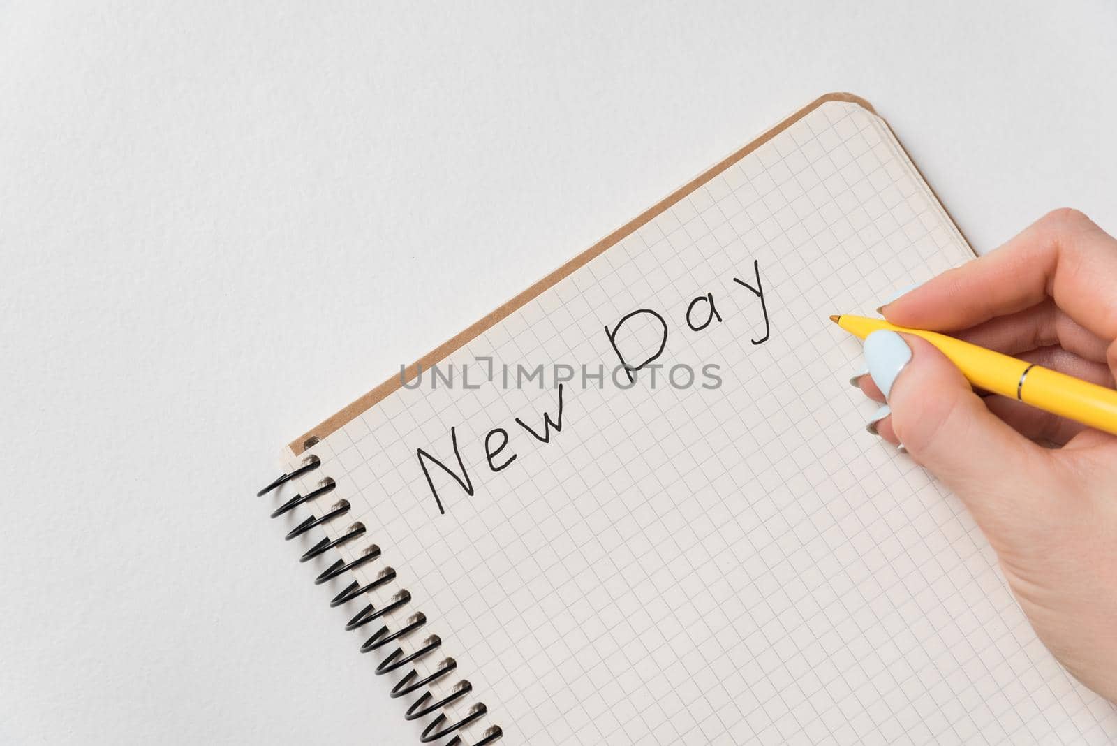 Words New Day in Notebook. Female hand writing in notebook. Handwritten. White background.