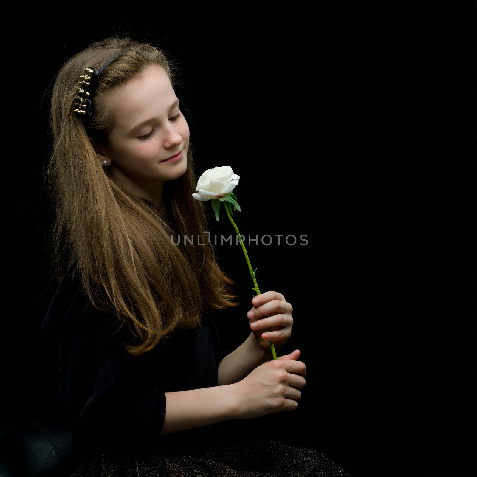 Cute little girl with white flower on a black background. The concept of style and fashion.