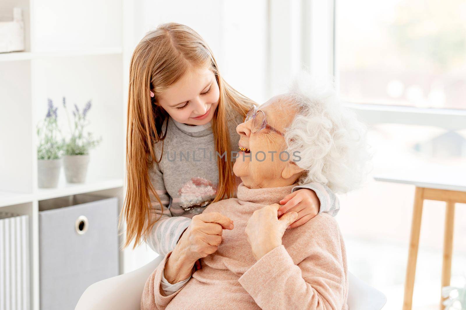 Lovely aged woman and little girl looking at each other at home