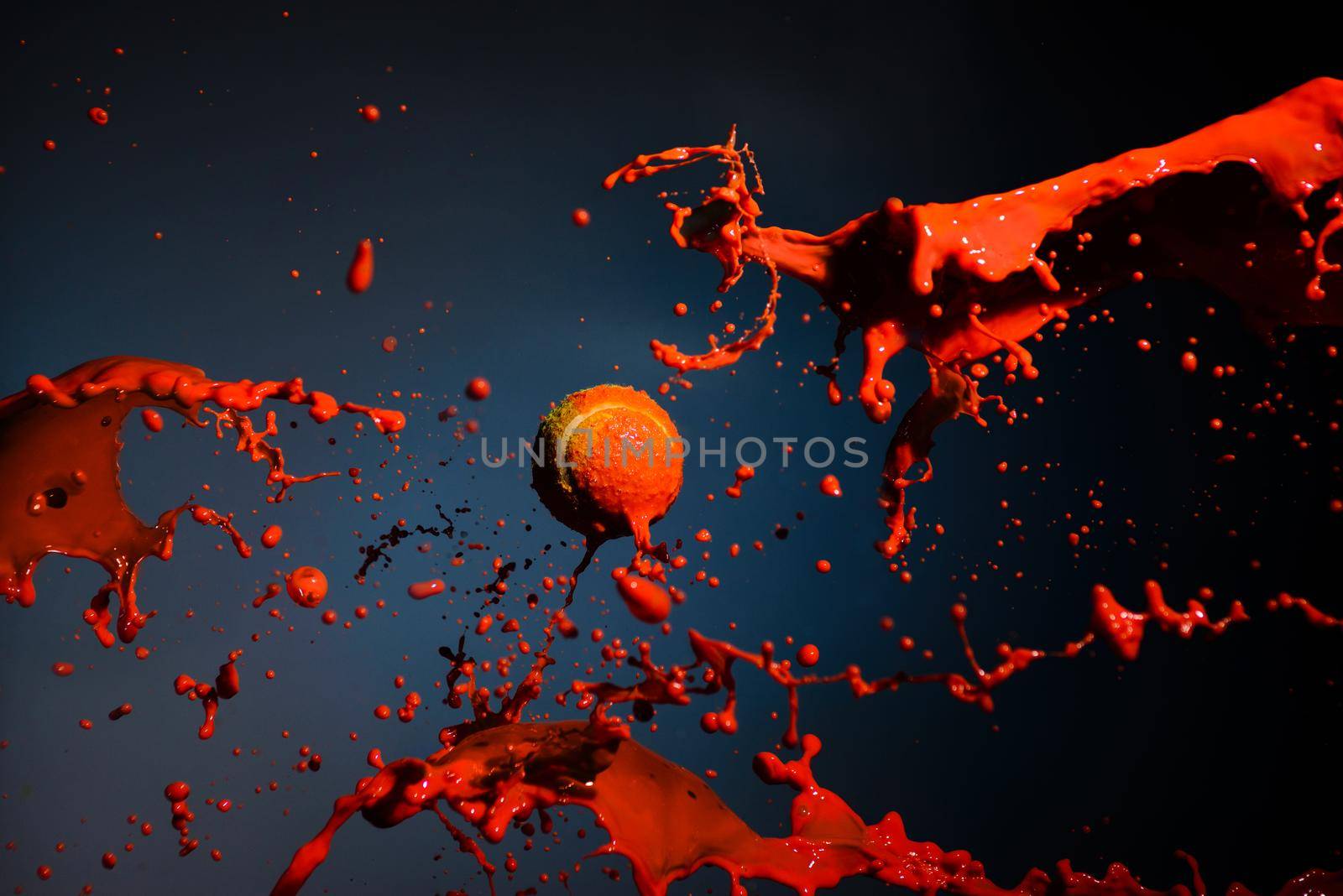 red paint splash and tennis ball on blue background.