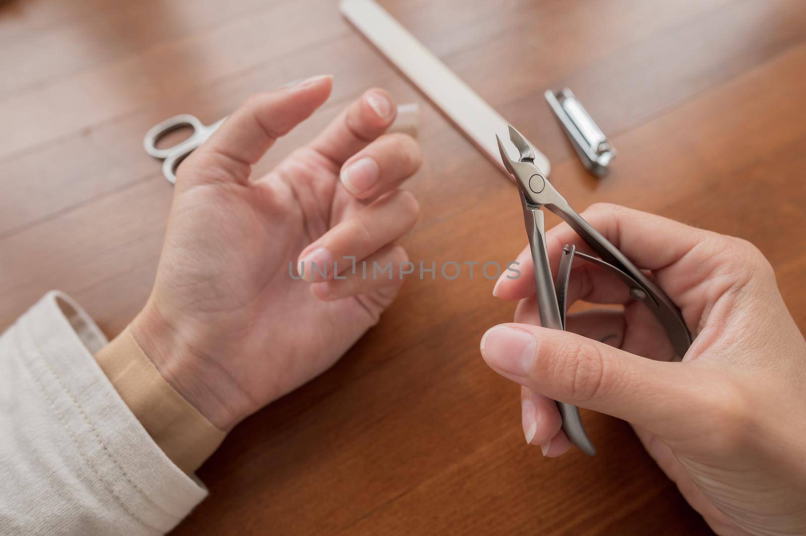 Caucasian girl makes herself a manicure at home. Close-up young woman uses nail clippers.