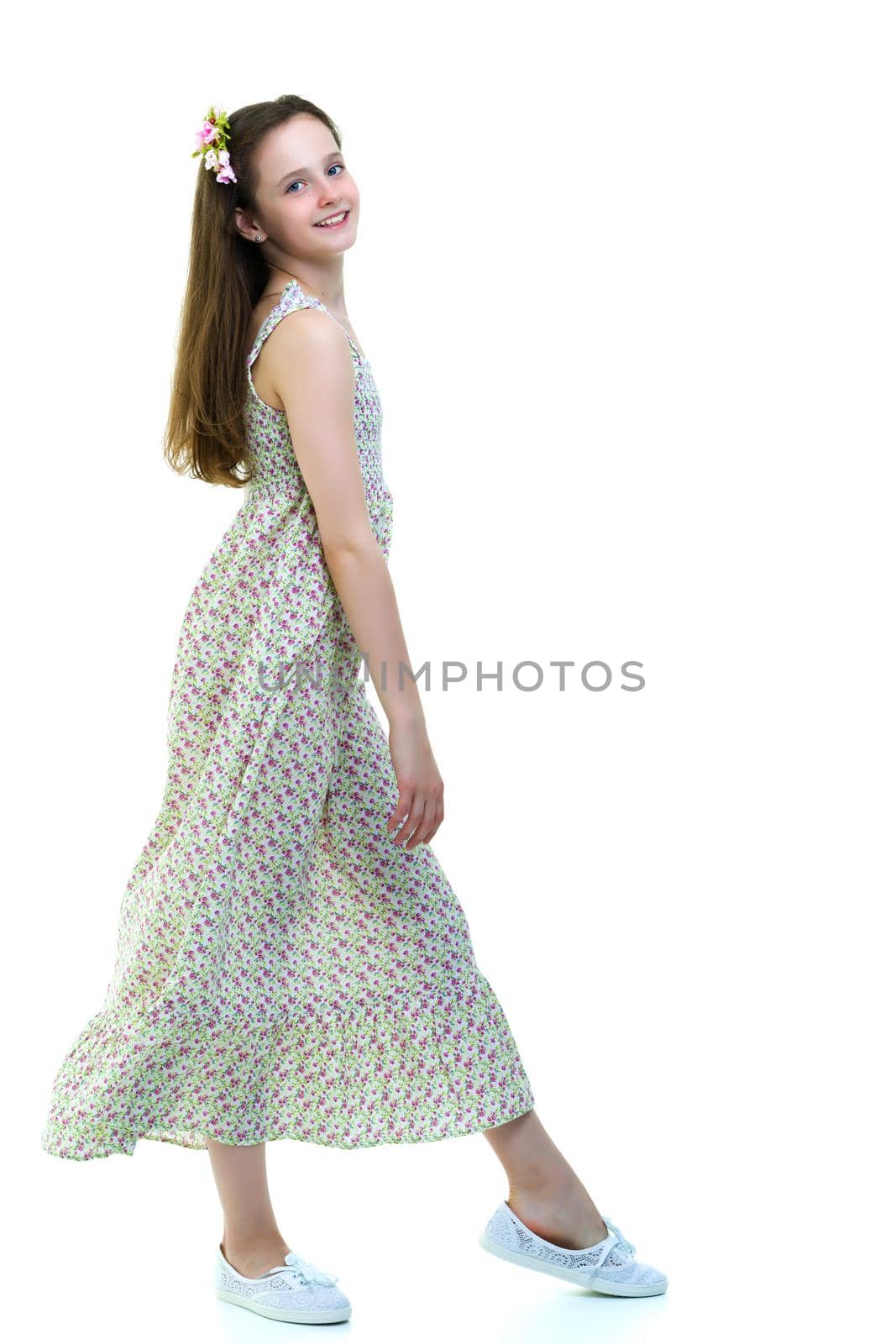 Beautiful little school girl with long silky hair. Studio portrait in full growth. Concept of style and fashion, happy people. Isolated on white background.