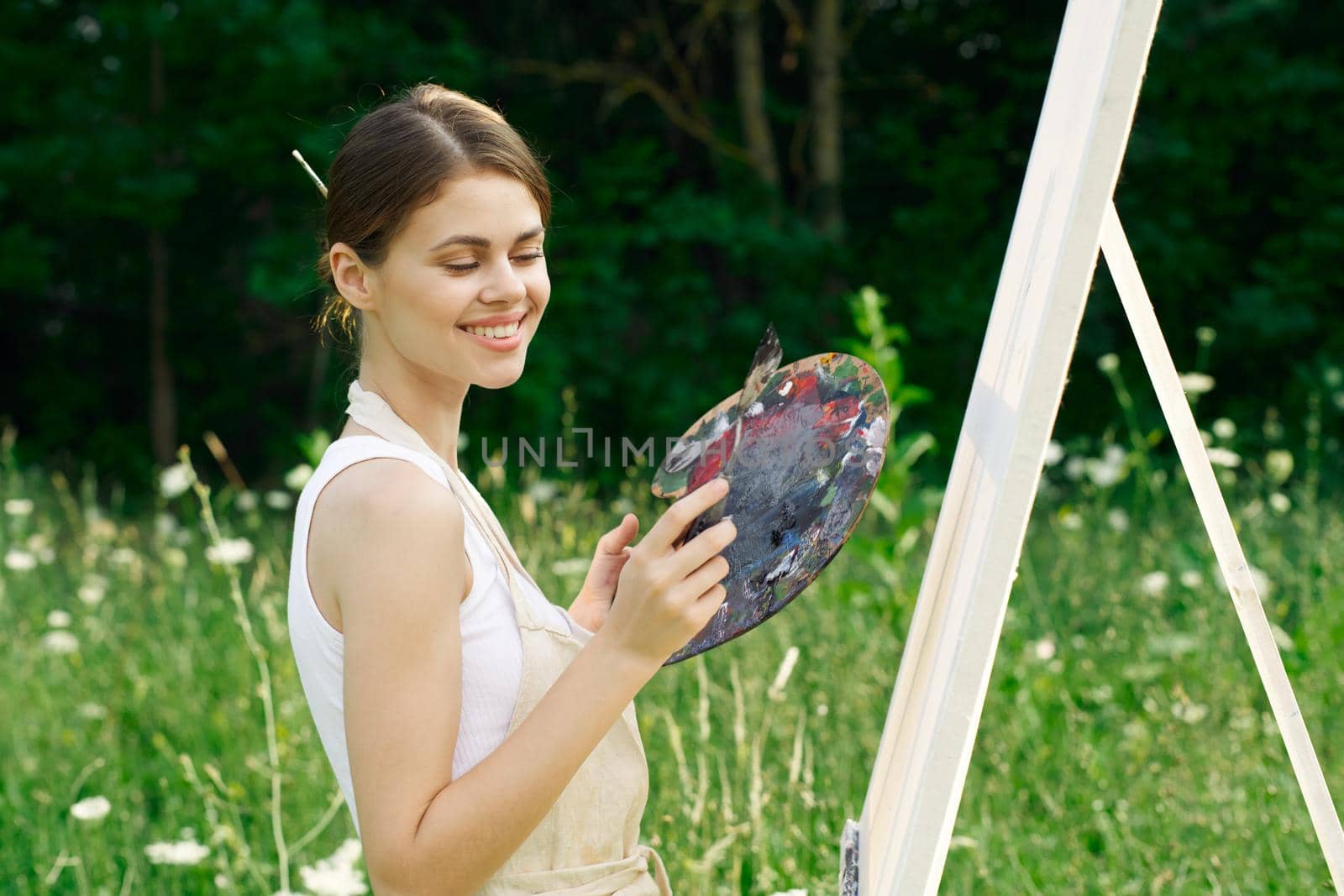 cheerful woman paints a picture palette nature landscape. High quality photo