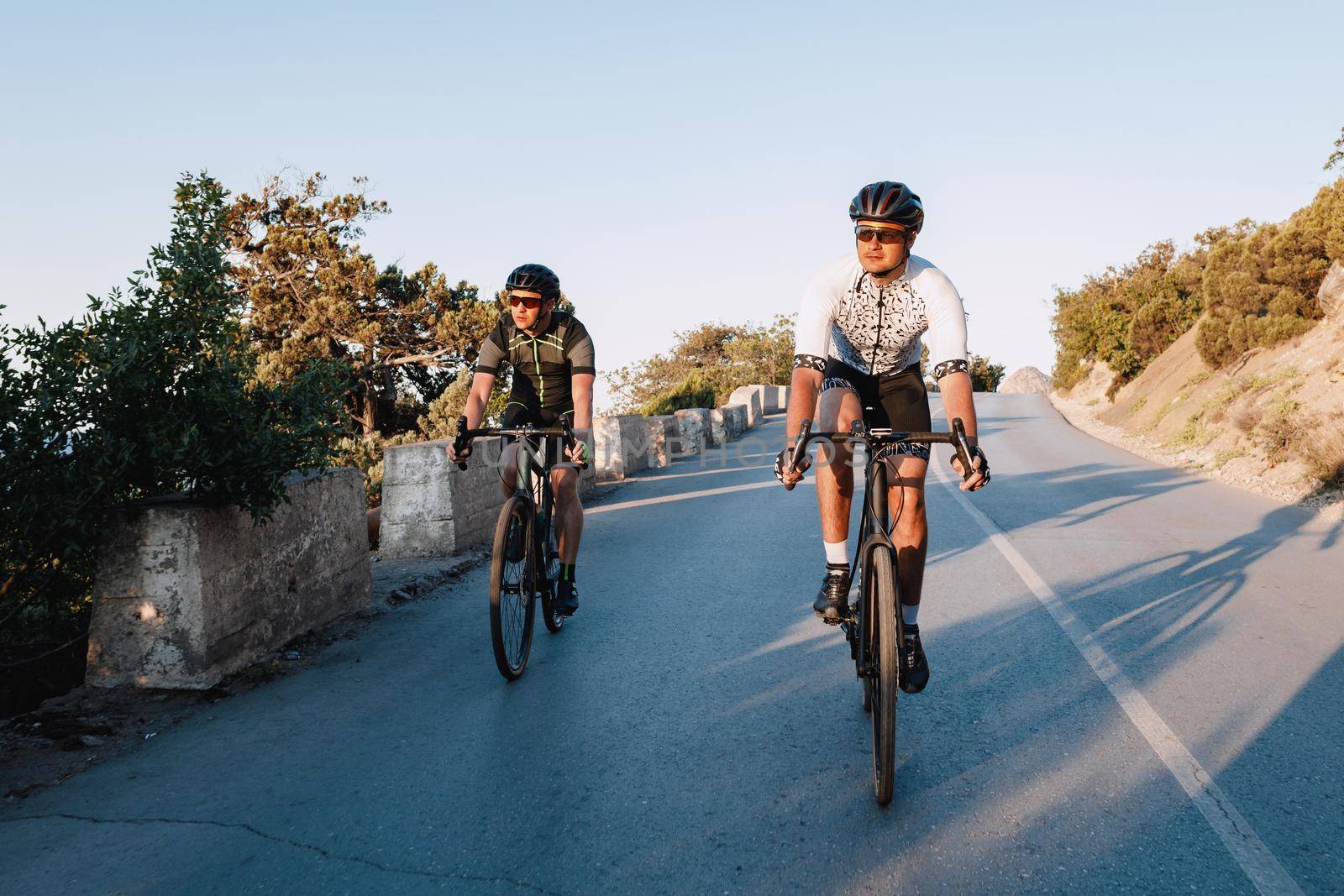 Two professional male cyclists riding their racing bicycles in the morning together on coastal road