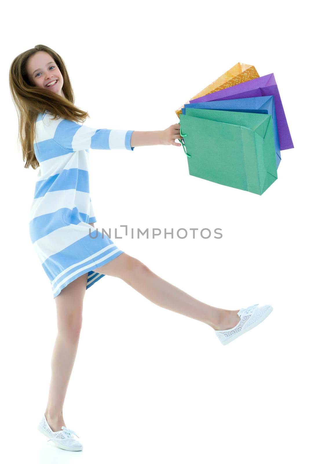 A cheerful little girl is shopping in a store with large, multi-colored paper bags. The concept of holidays, advertising sales. Isolated on white background.