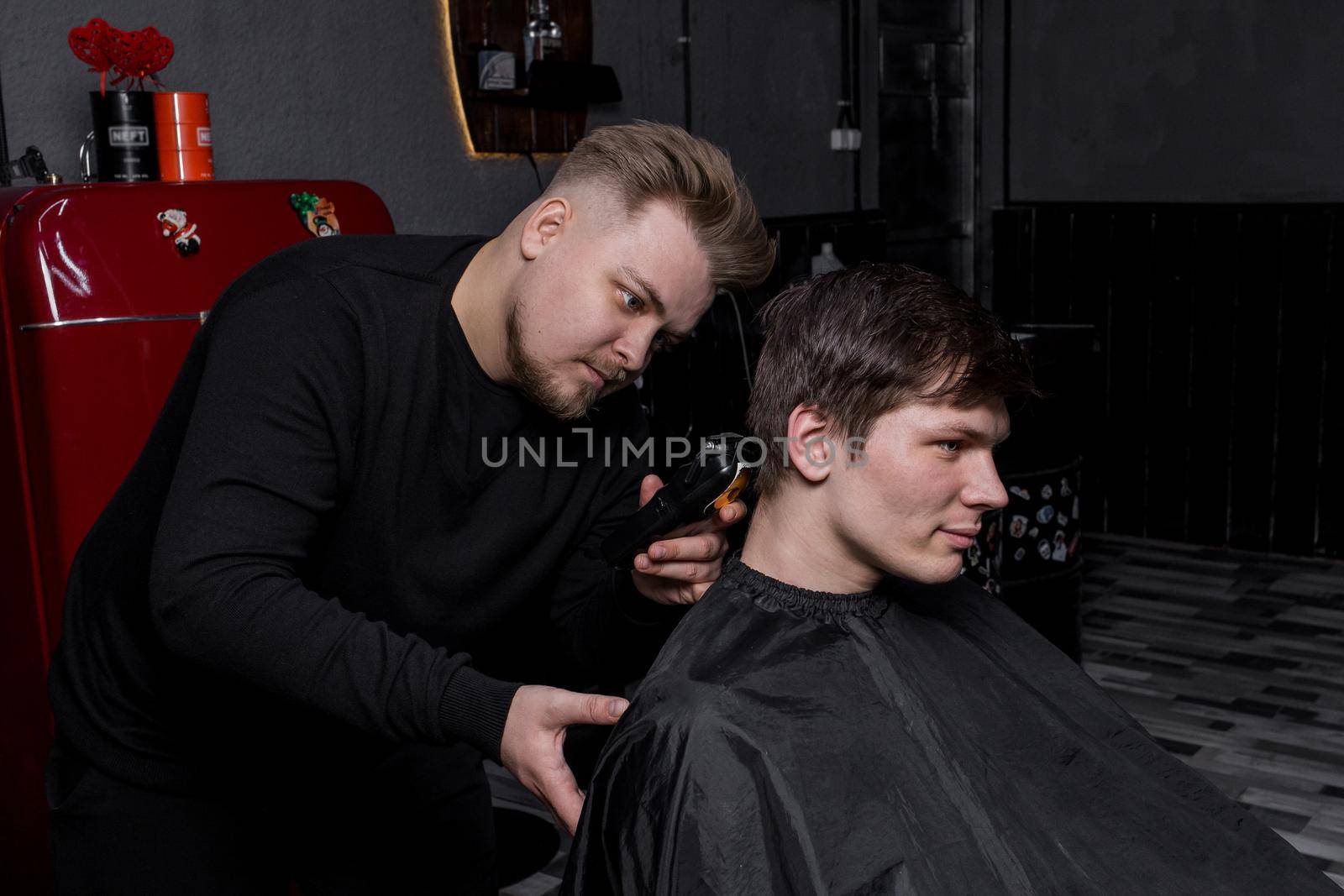 Barber European looking man hairdresser cuts the client with dark hair. Hairdressing by AYDO8