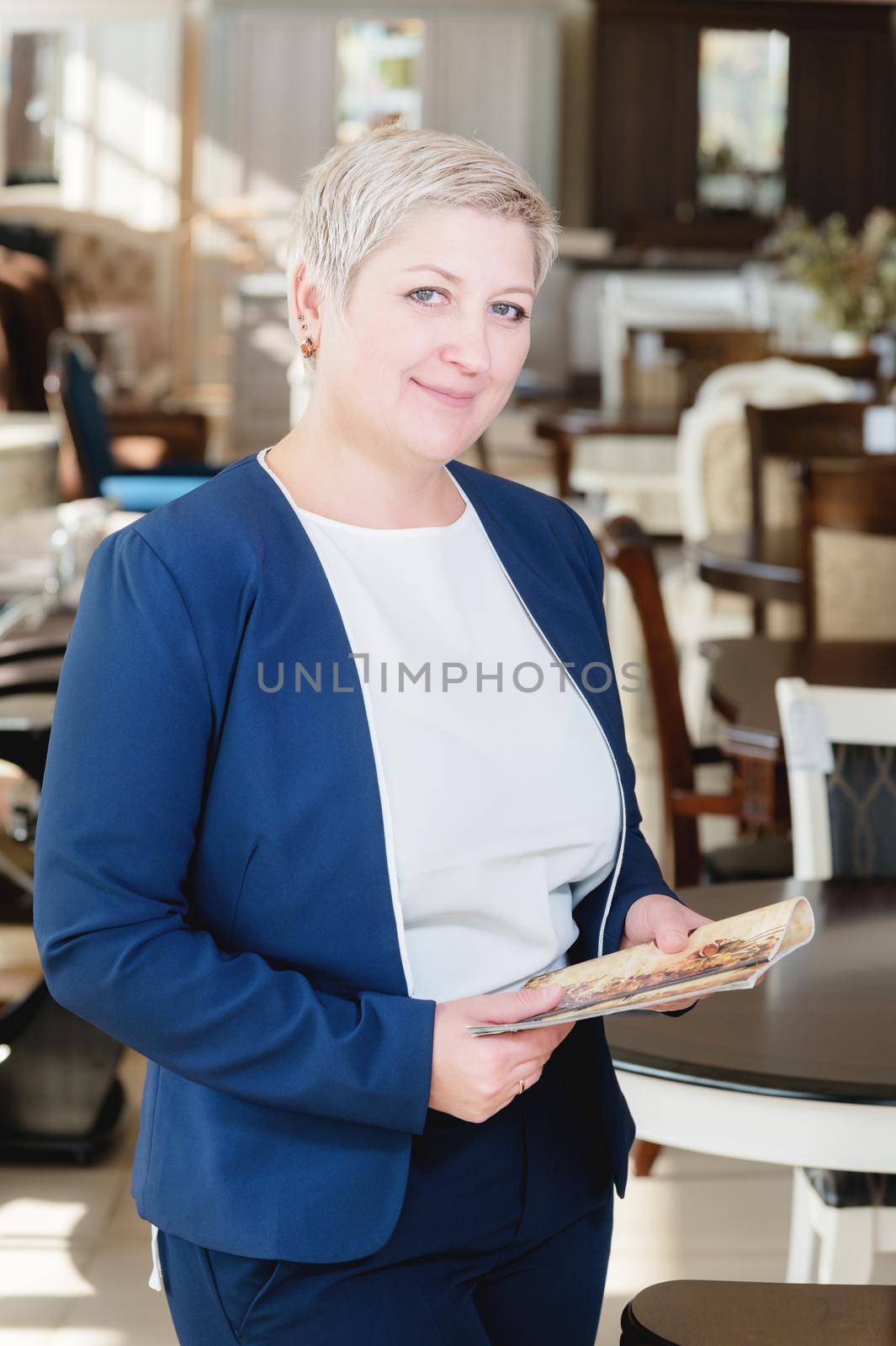 Portrait of a middle-aged business woman. The owner and director of the furniture business is standing near the table. Strong woman with a short haircut by yanik88