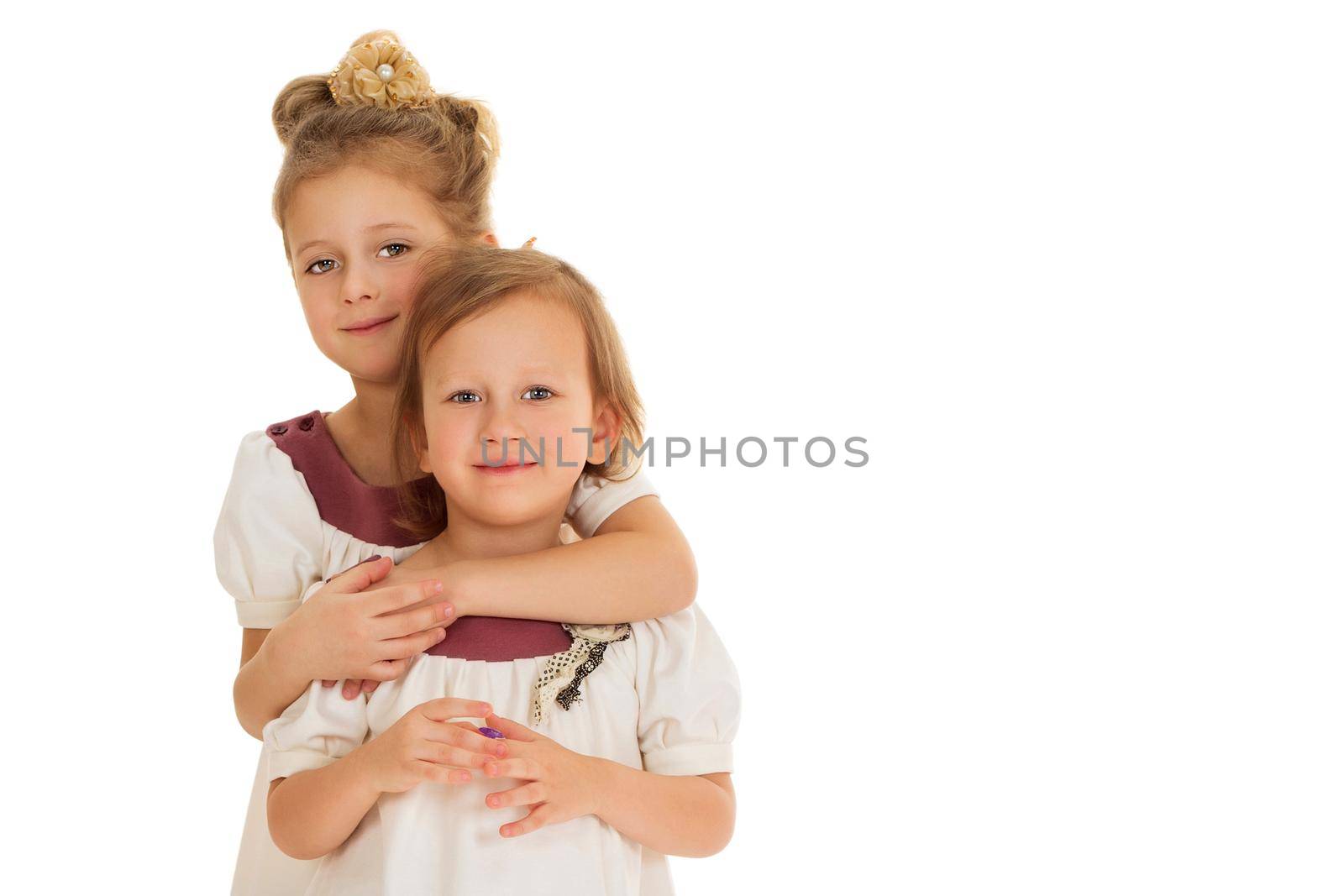 Girls in matching dresses hug - Isolated on white background