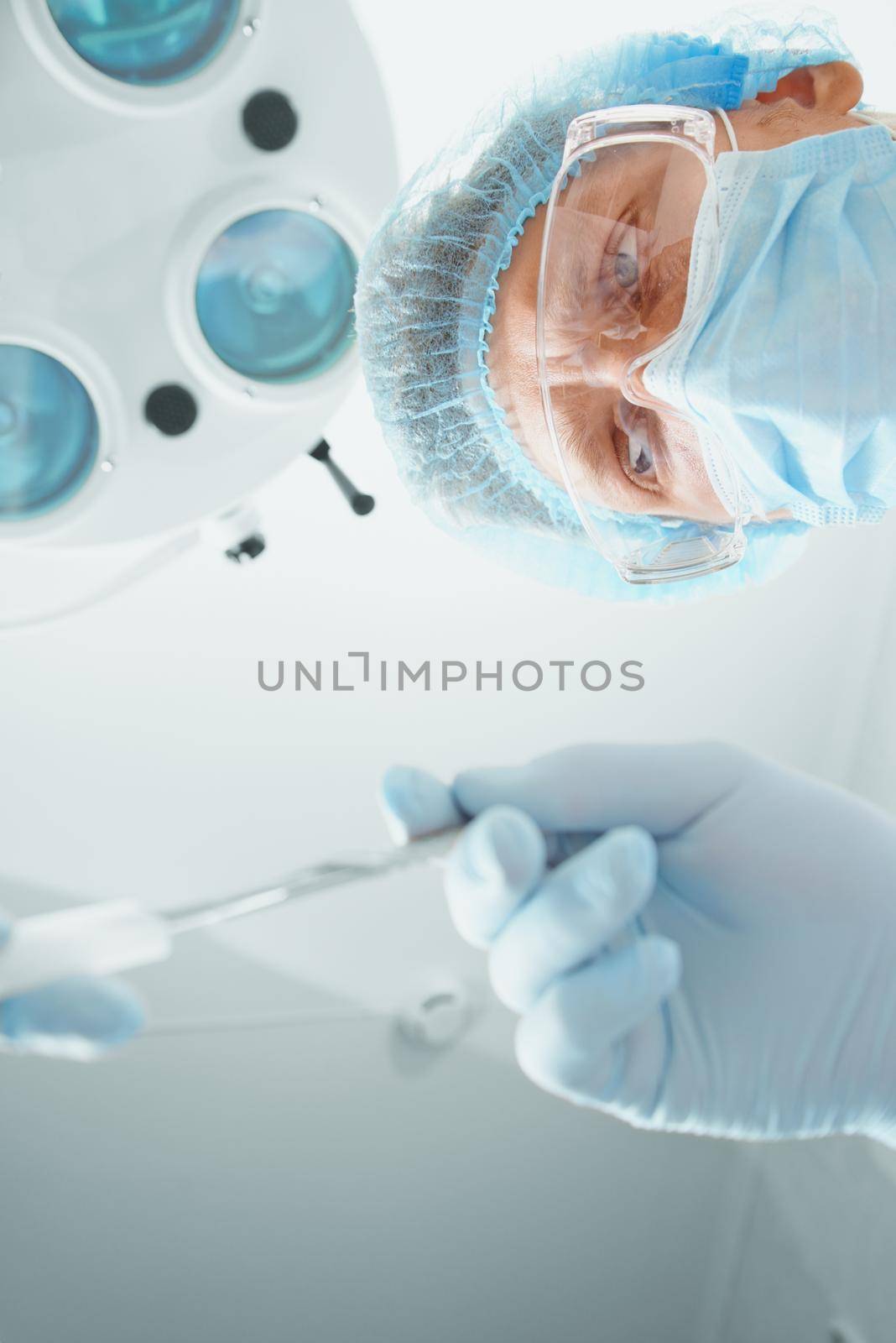 Man surgeon in protective uniform takes a scalpel on operation