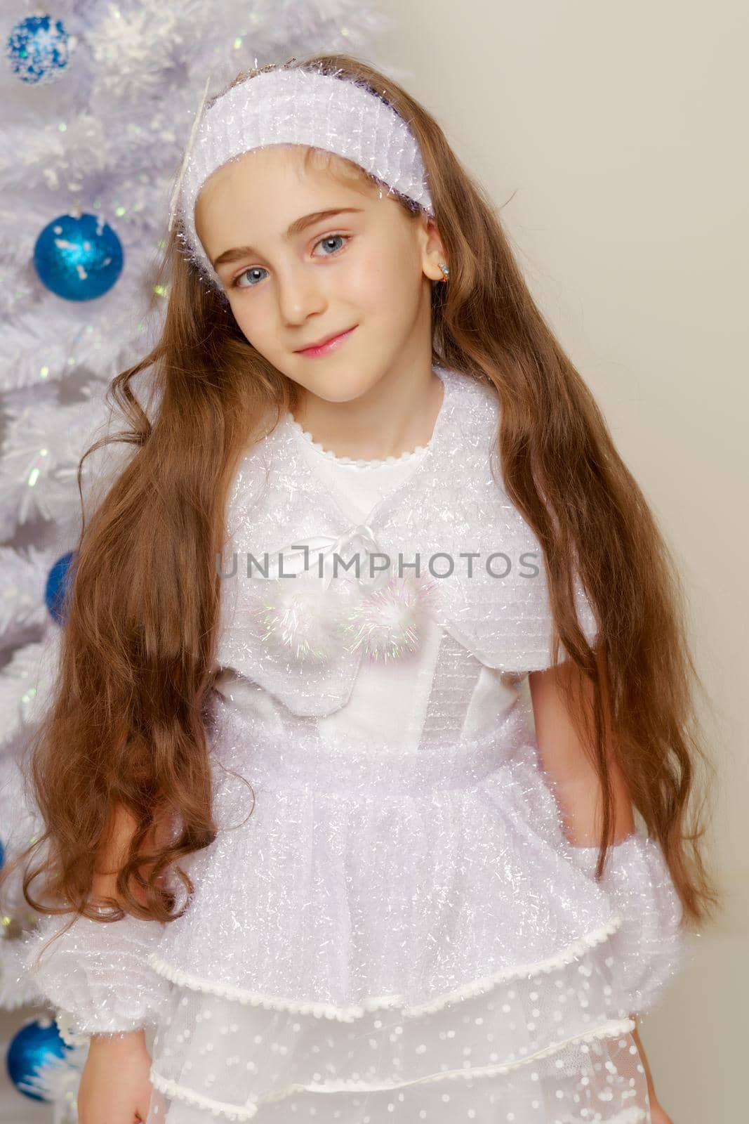 Beautiful little girl near the Christmas tree. The concept of family holidays, children's emotions.