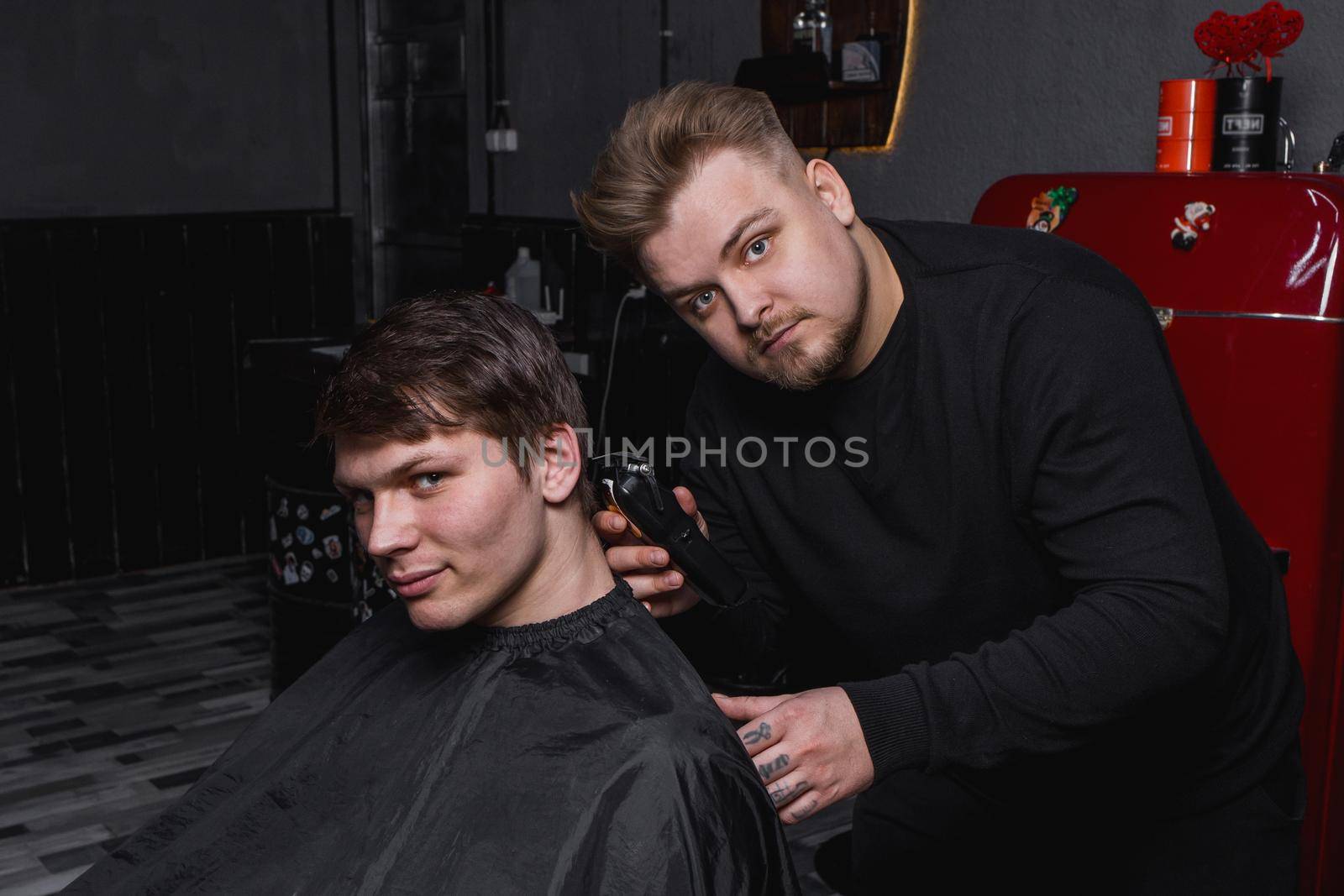 Barber European looking man hairdresser cuts the client with dark hair. Hairdressing.