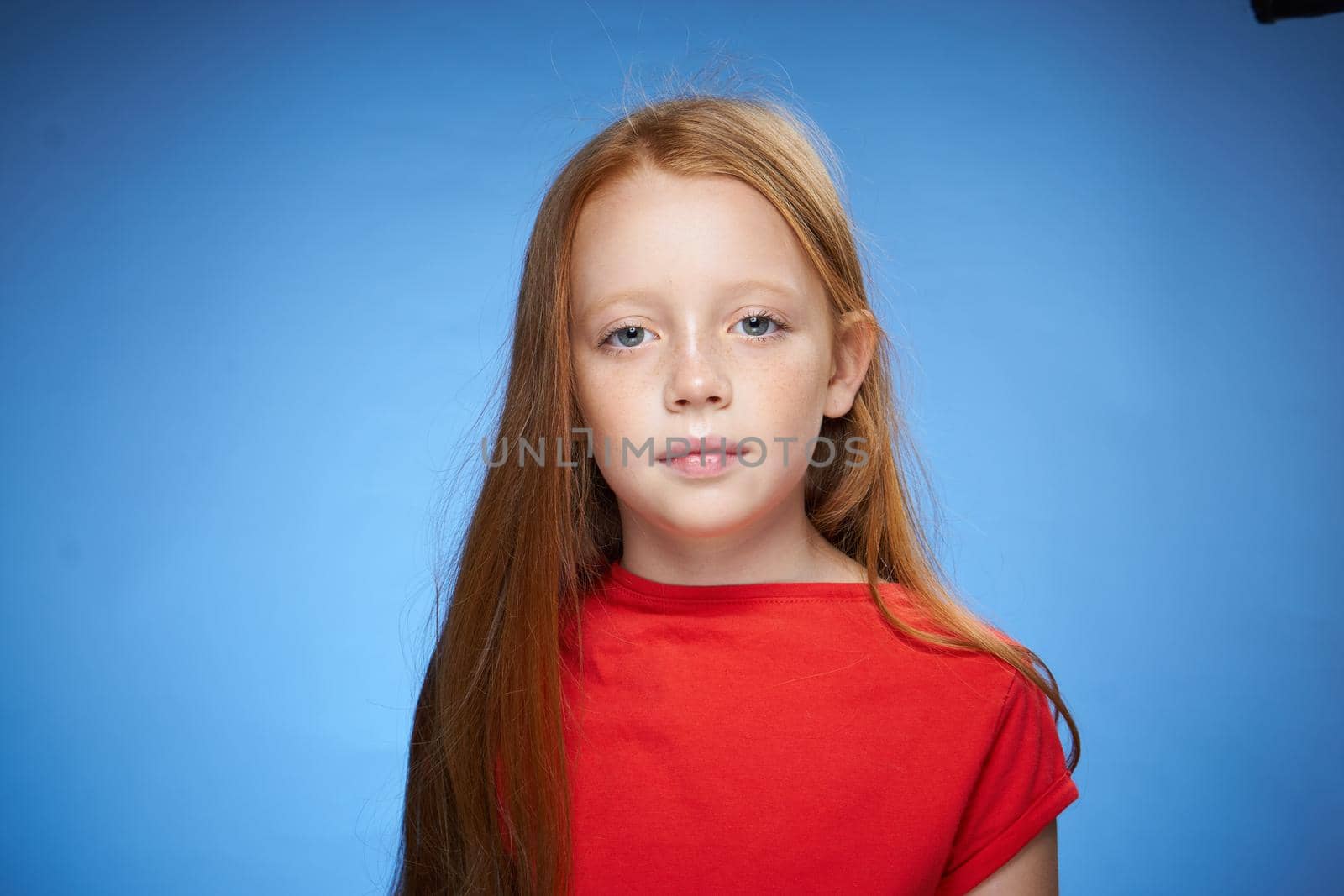 cheerful cute red-haired girl childhood blue background. High quality photo