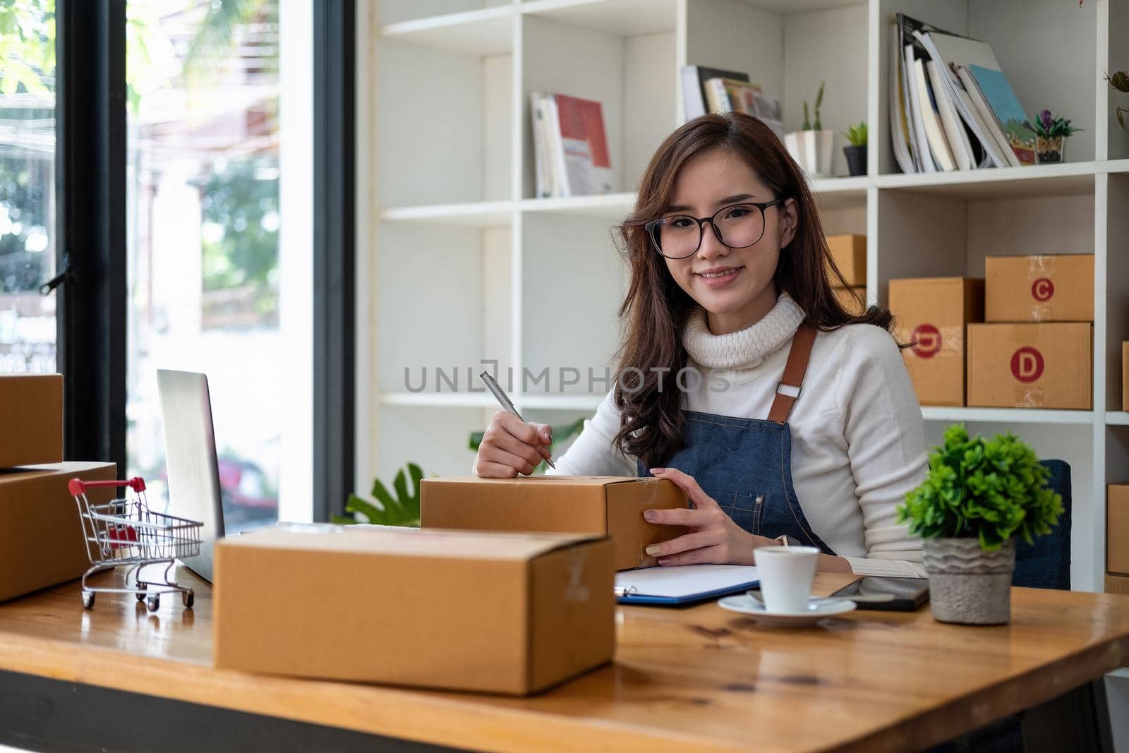 Starting Small business entrepreneur SME freelance,Portrait young woman working at home office, BOX,smartphone,laptop, online, marketing, packaging, delivery, SME, e-commerce concept