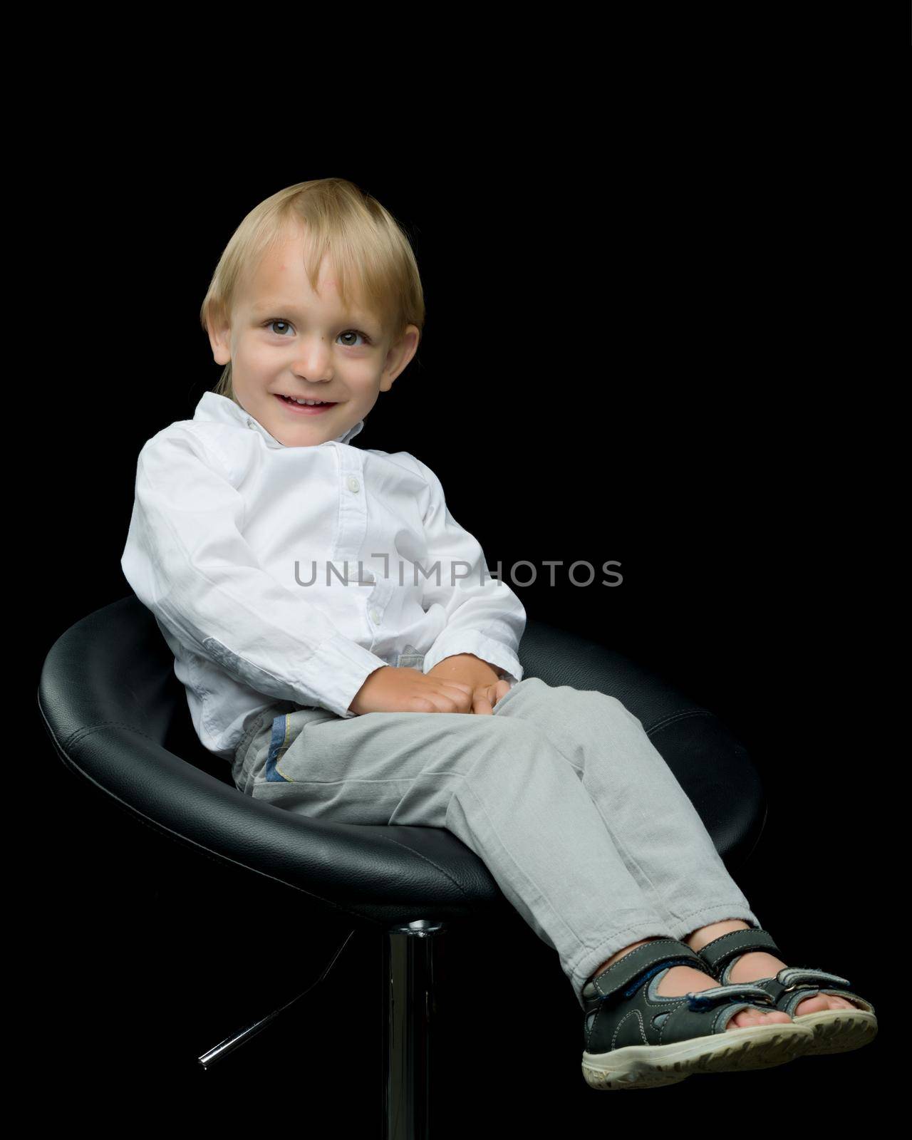 A cute little boy is sitting on a chair. by kolesnikov_studio