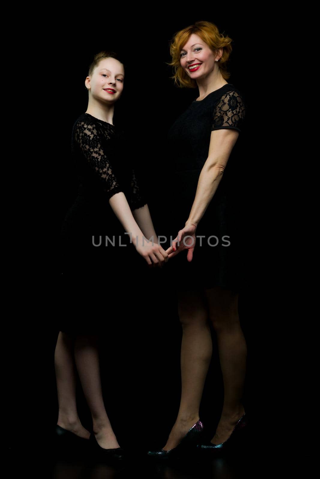 Happy family mom and little daughter, studio portrait.On black background