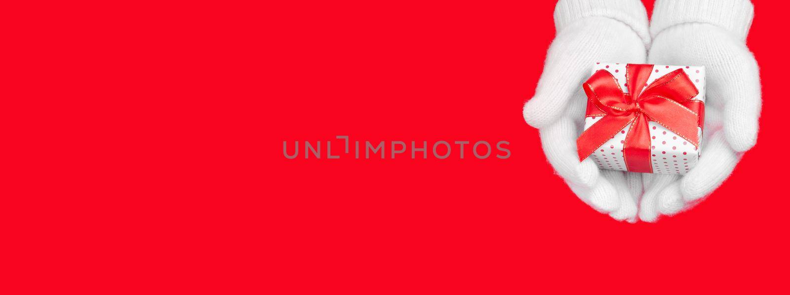 Banner for the site a gift in soft white gloves on a red background with a place for the text. Charity, christmas and holiday discounts concept