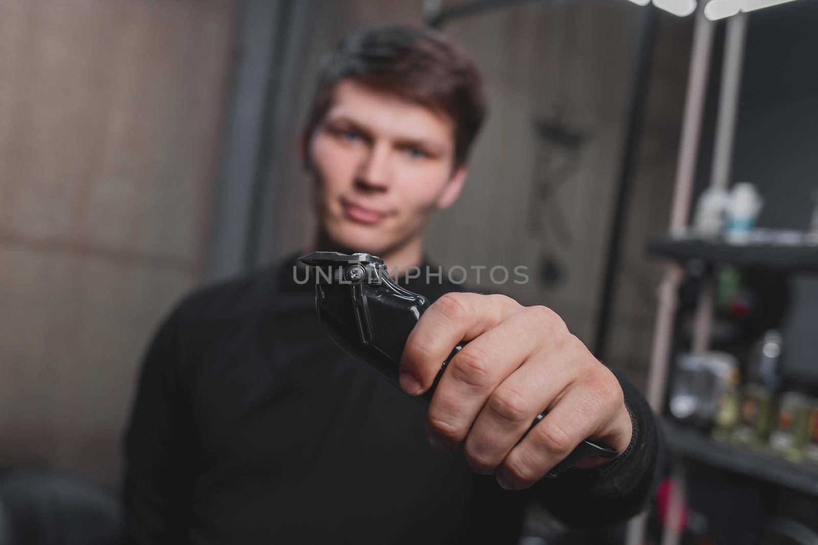 A guy holds an electric shaving machine. Hairdressing.