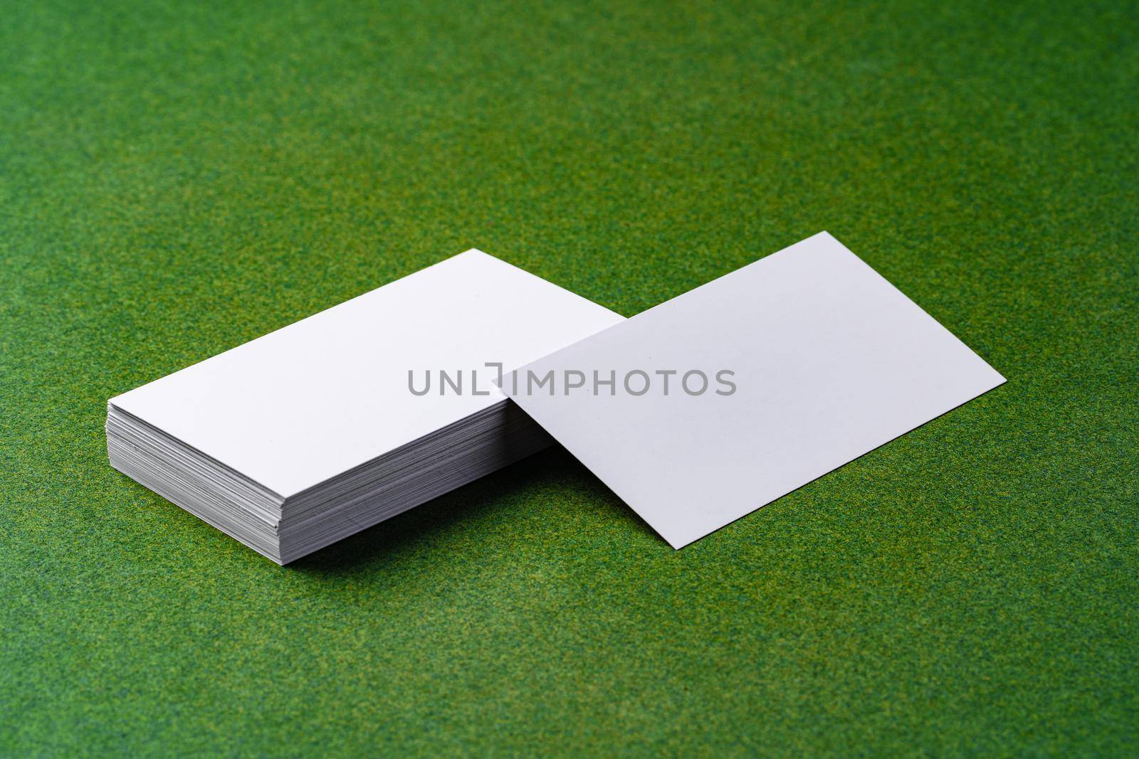 Stacks of white business cards on dark green background, close up
