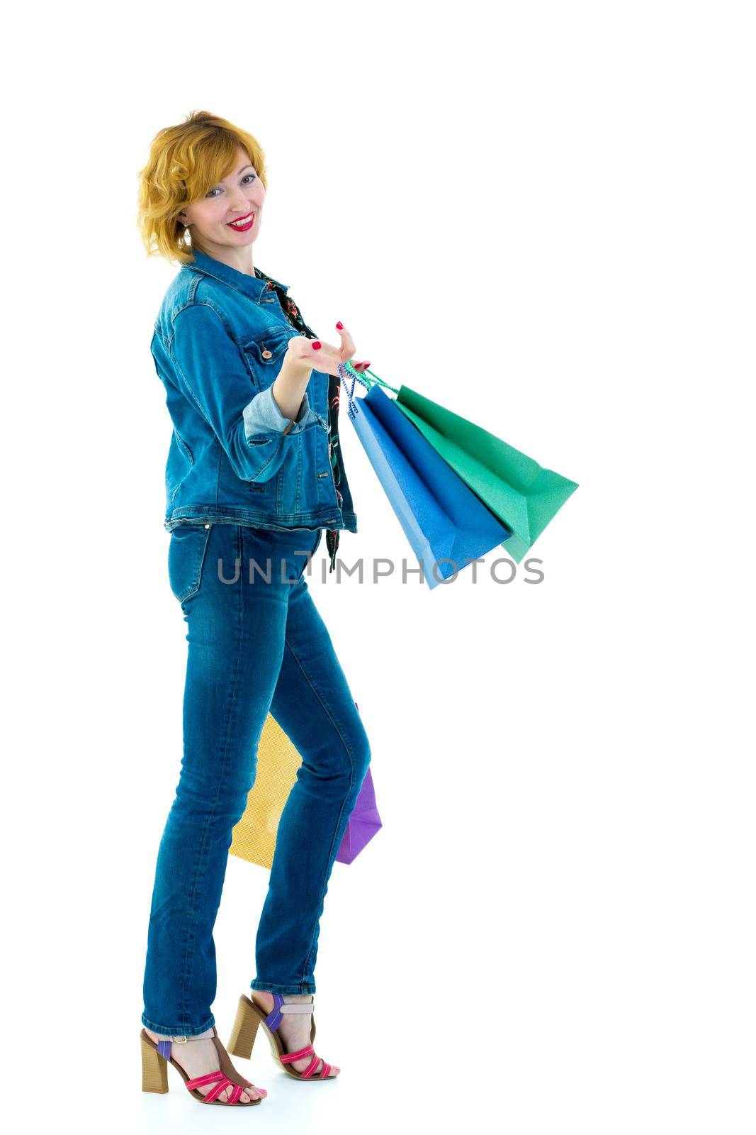 A beautiful young woman happily shopping with large multi-colored paper bags. The concept of sales, upcoming holidays. Isolated on white background.