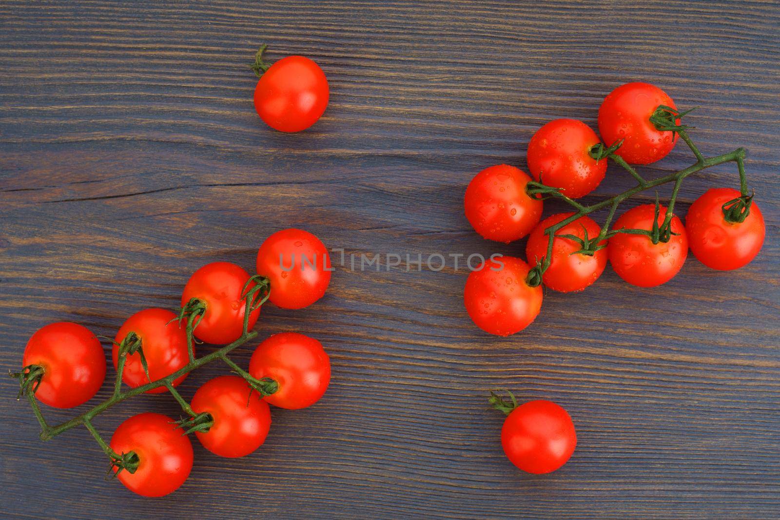 Ripe cherry tomatoes on a twig on a dark woden background by zartarn