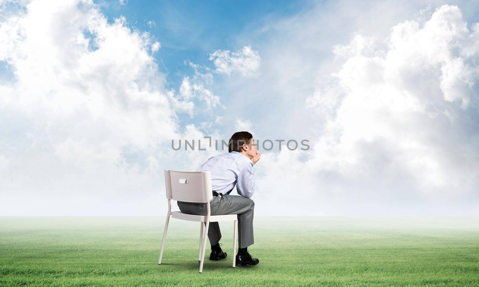 young businessman sits on an office chair, thoughtful and looking up