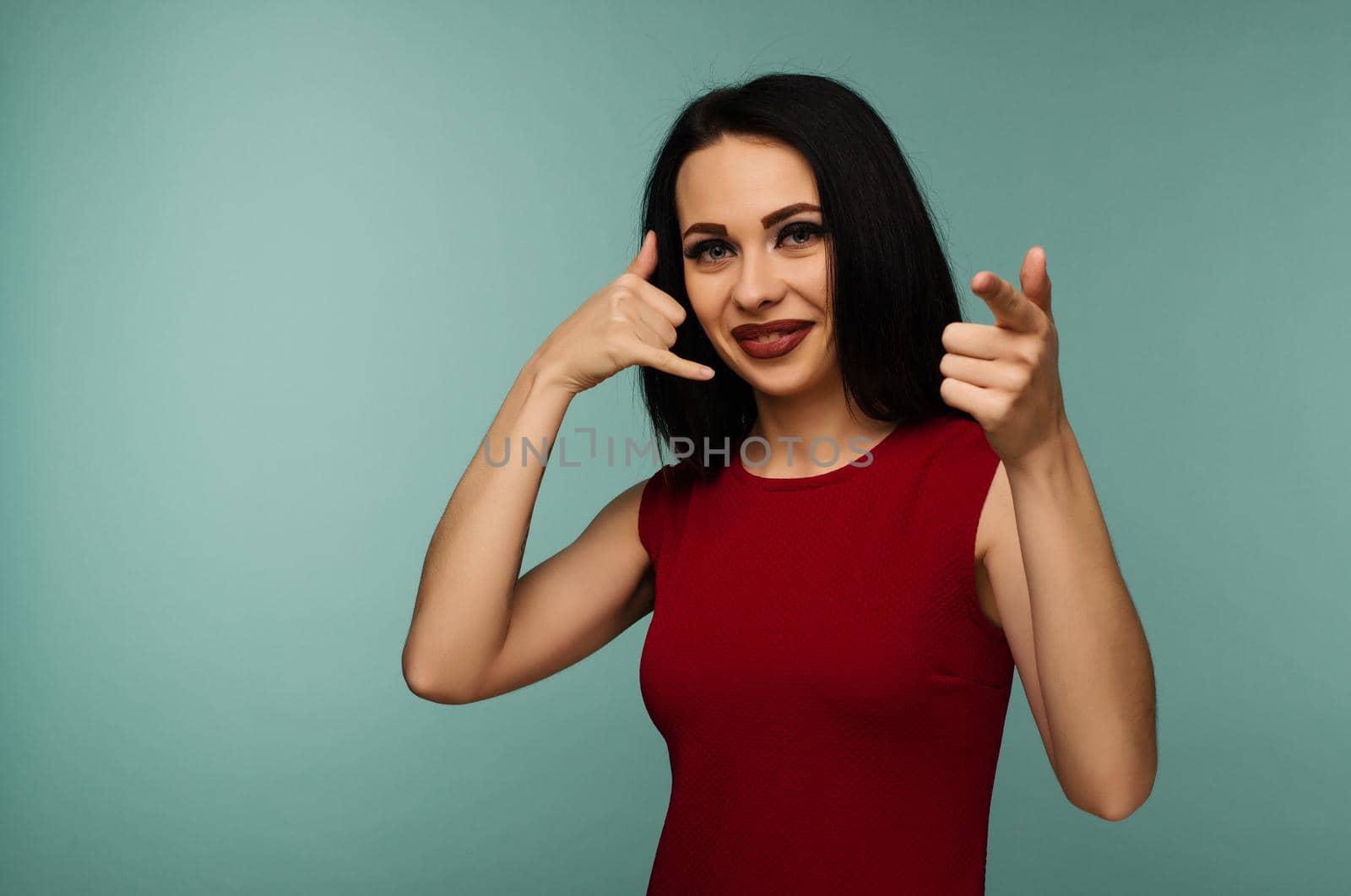 Portrait of an young woman looking and pointing at you saying call me on isolated background - Image