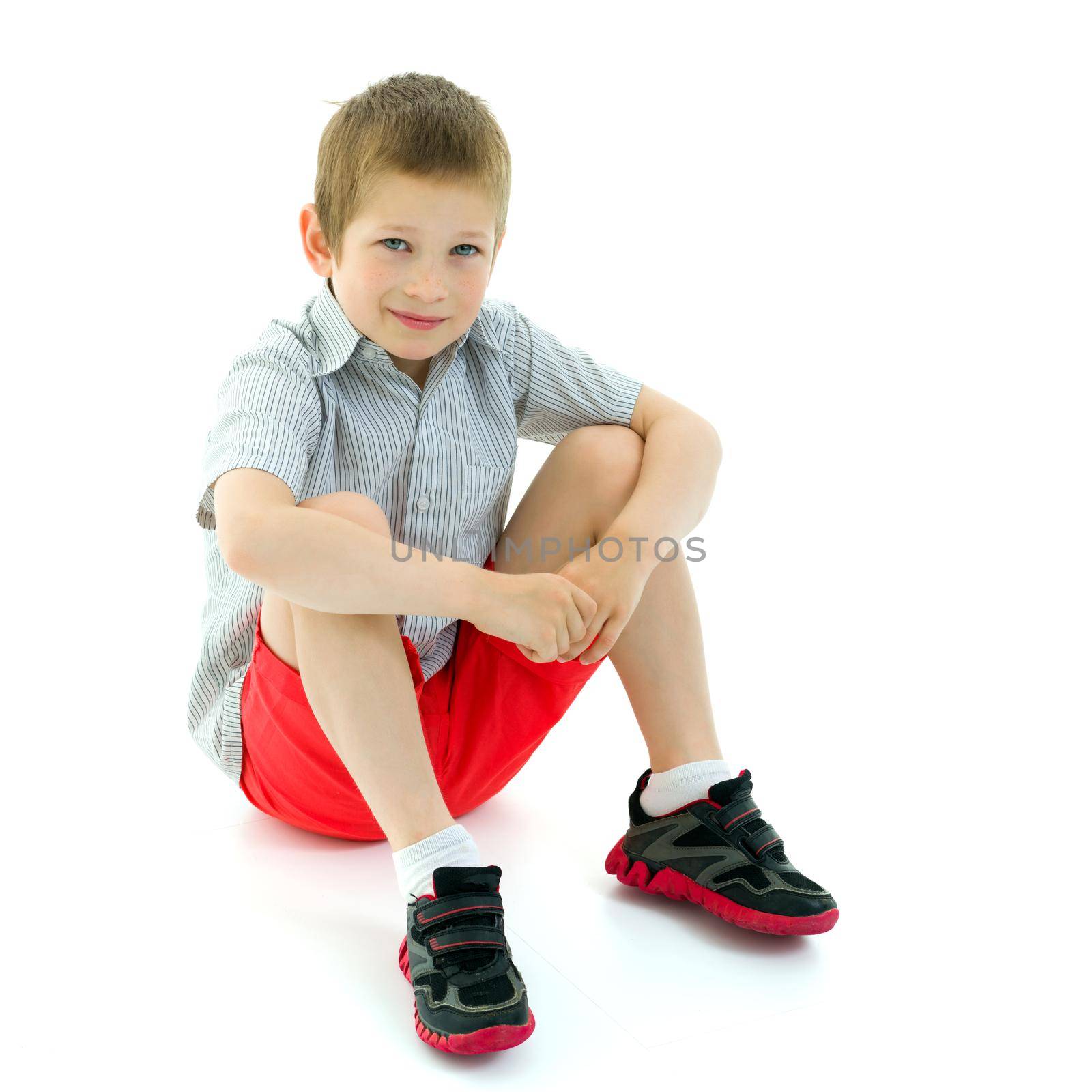 Cute little boy is sitting on the floor on a white background. The concept of a happy childhood, the harmonious development of the child in the family. Isolated.