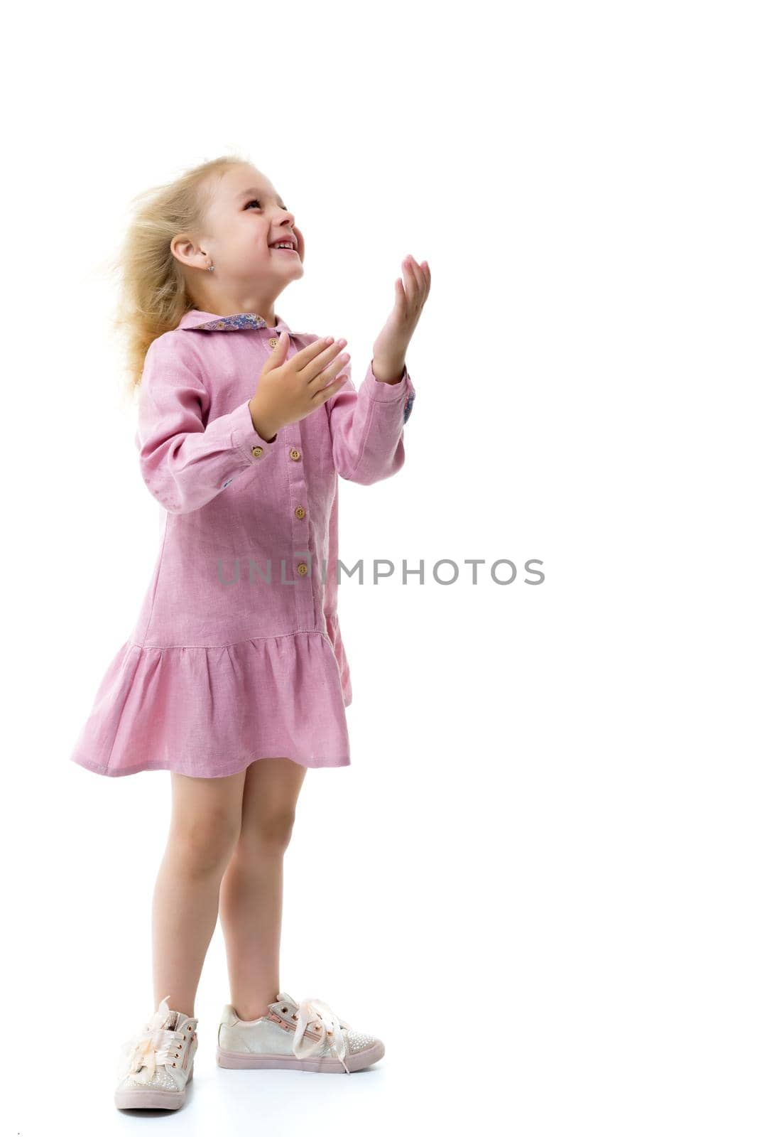 Portrait of a positive and stylish little girl in a summer dress, rejoices in the wind that blows and moves her dress and hair. The concept of beauty and fashion. Isolated on white background.