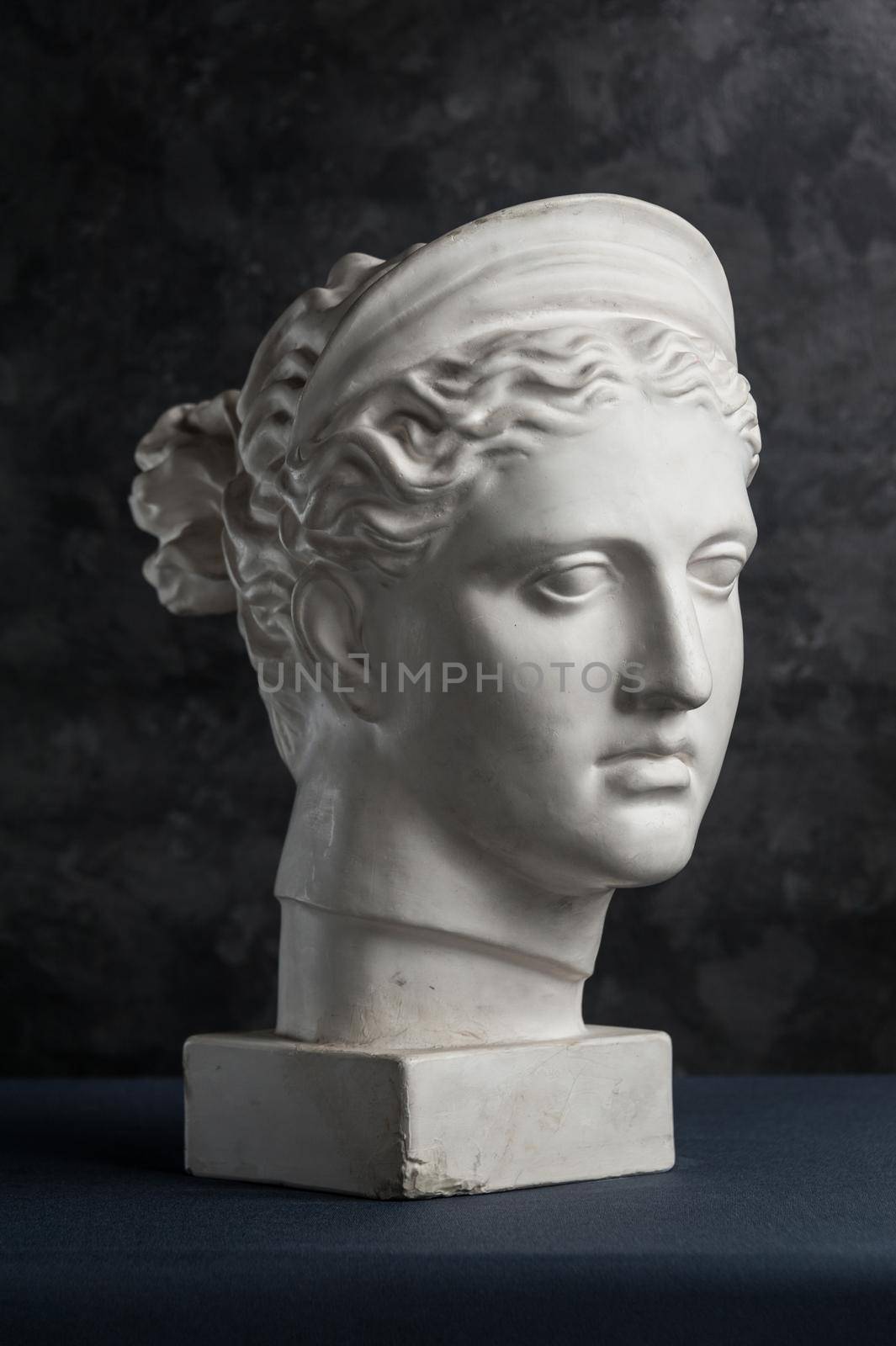 White gypsum copy of ancient statue of Diana head for artists on a dark textured background. Plaster sculpture of woman face. Diana in Roman mythology the goddess of nature and hunting.