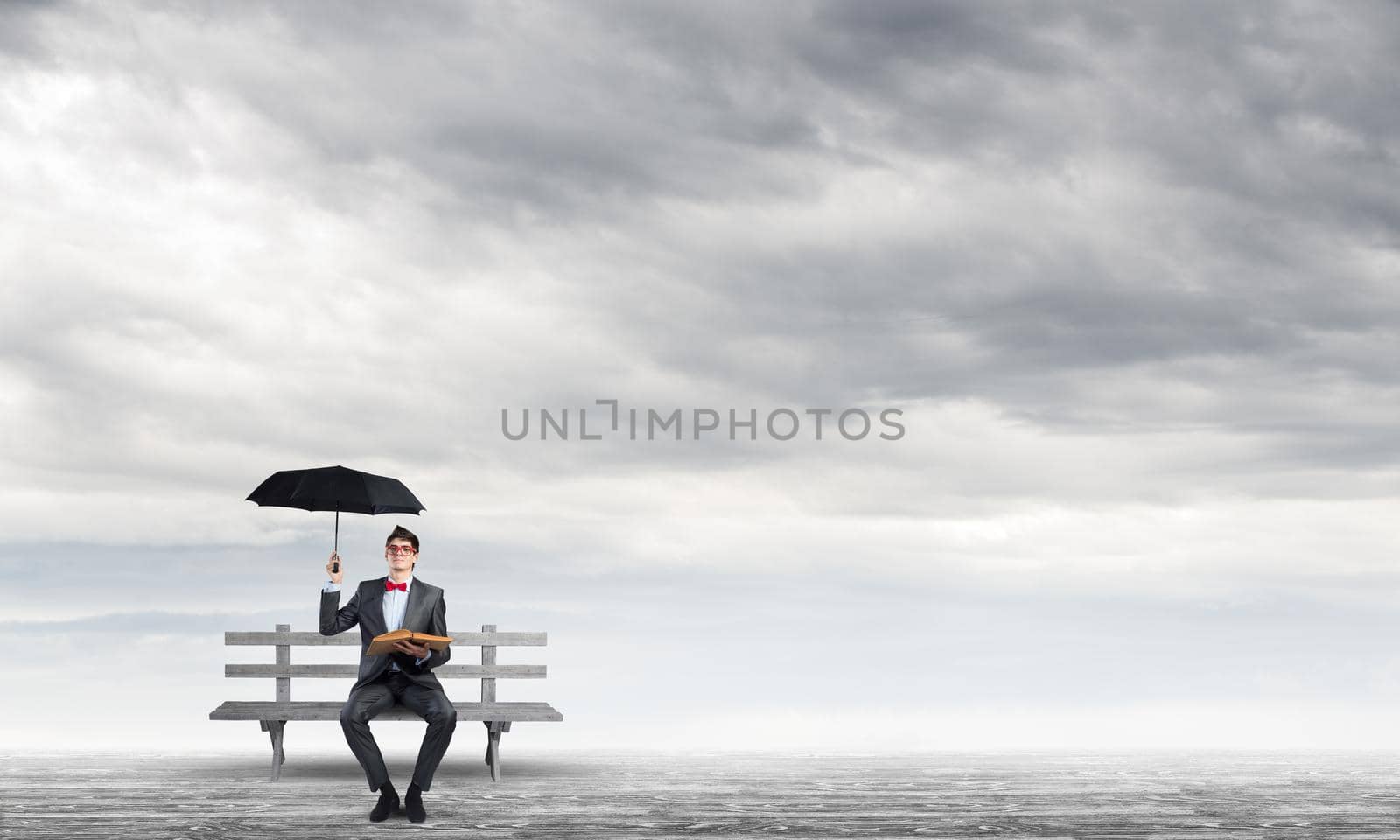 young student with umbrella and book sits on a bench