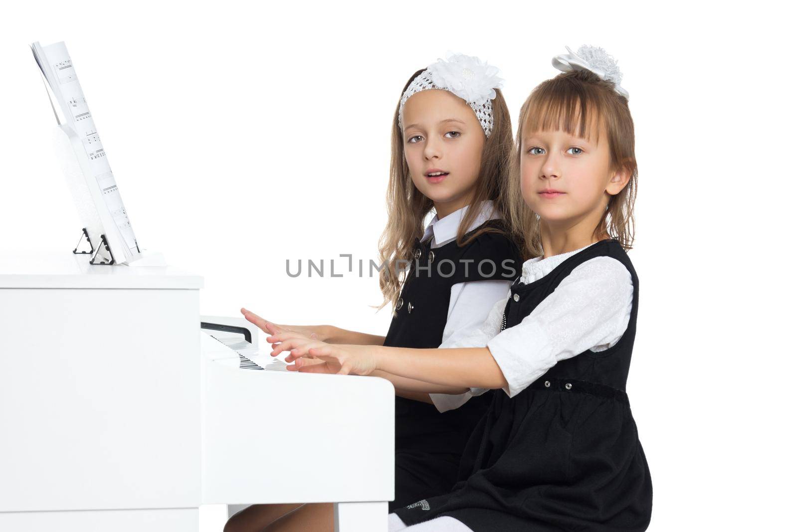Two girls of preschool age diligently play the piano - Isolated on white background