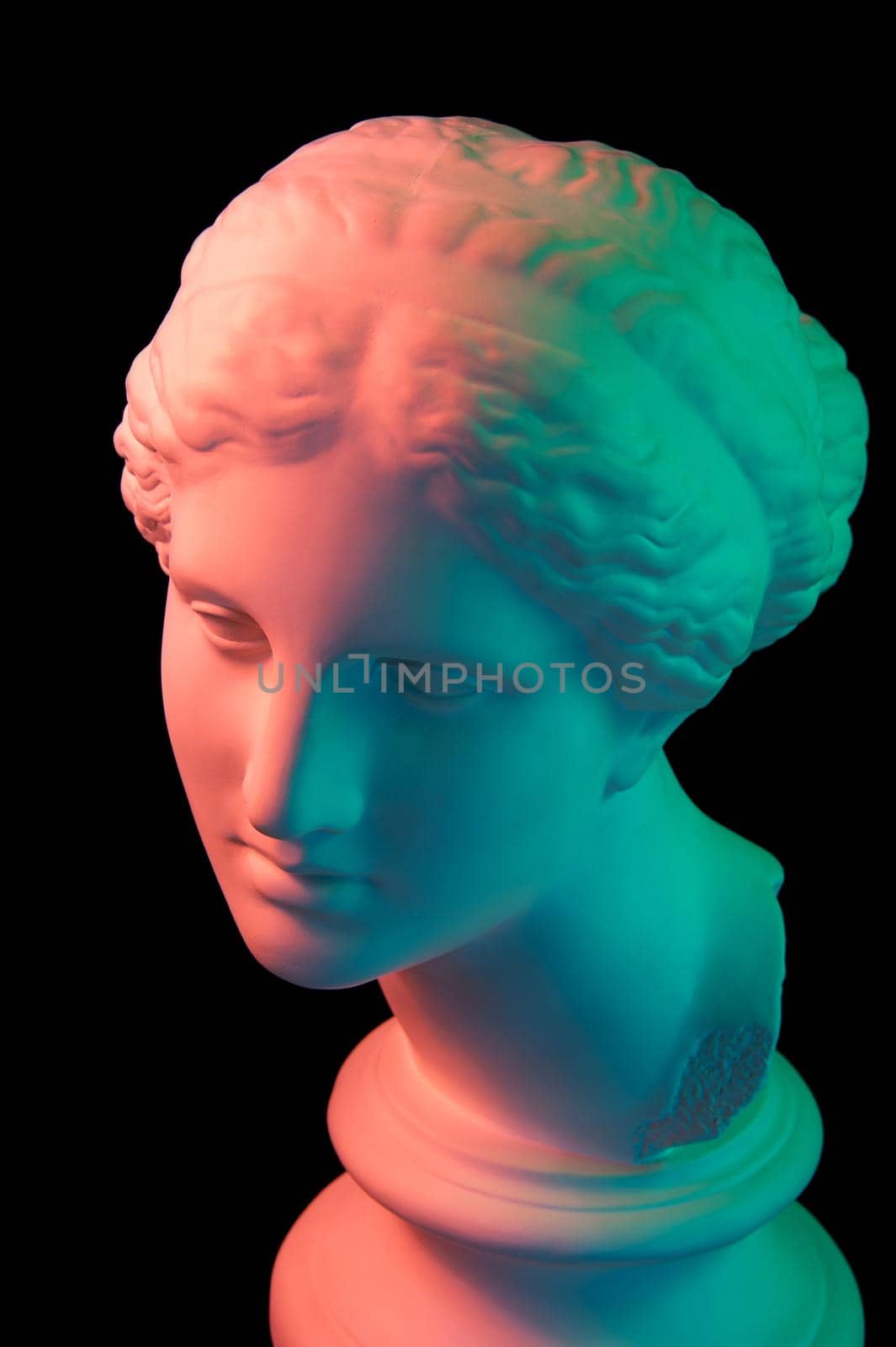 Gypsum copy of ancient statue of Venus de Milo head for artists isolated on a black background. Plaster sculpture of woman face. Multi color toned.