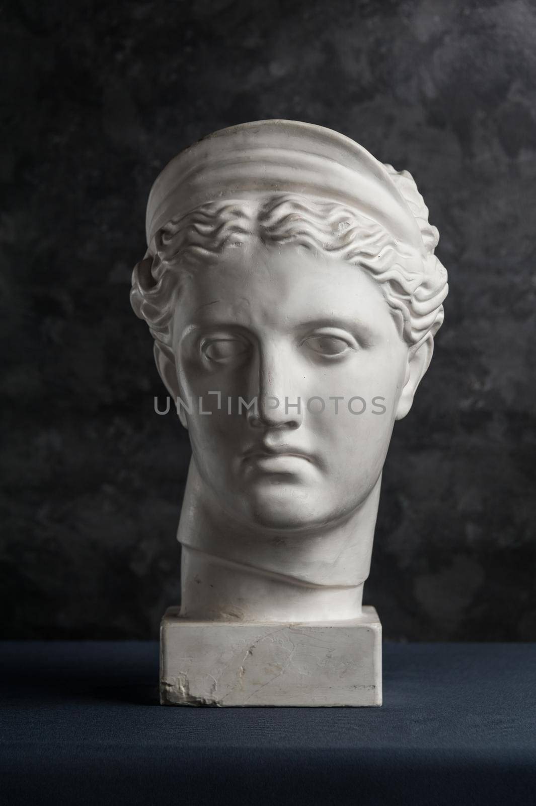 White gypsum copy of ancient statue of Diana head for artists on a dark textured background. Plaster sculpture of woman face. Diana in Roman mythology the goddess of nature and hunting.