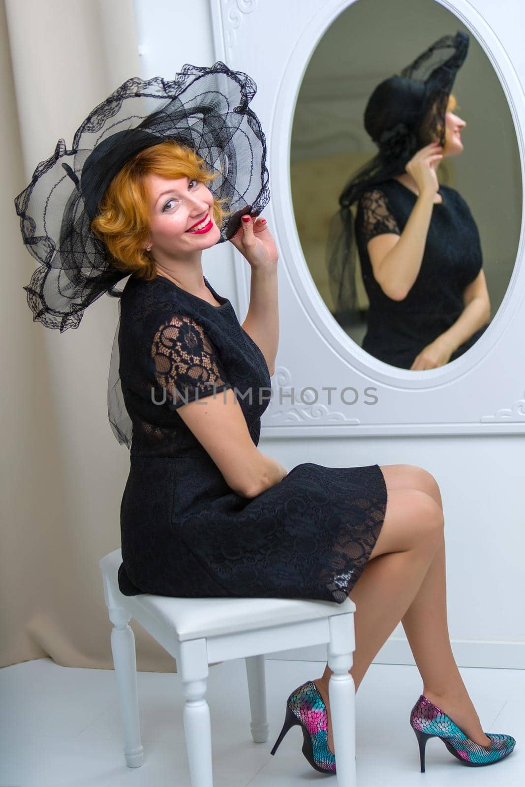 Stylish young woman in a luxurious hat near the mirror. The concept of beauty and fashion.