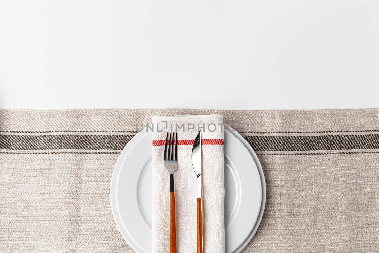 Fork, knife and plate on towel. Isolated on white background. Close up.
