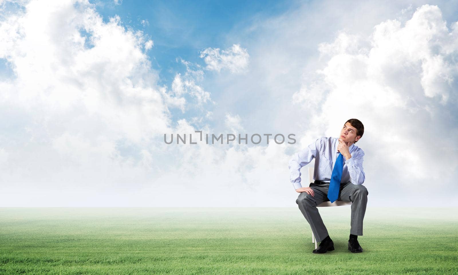young businessman sits on an office chair, thoughtful and looking up