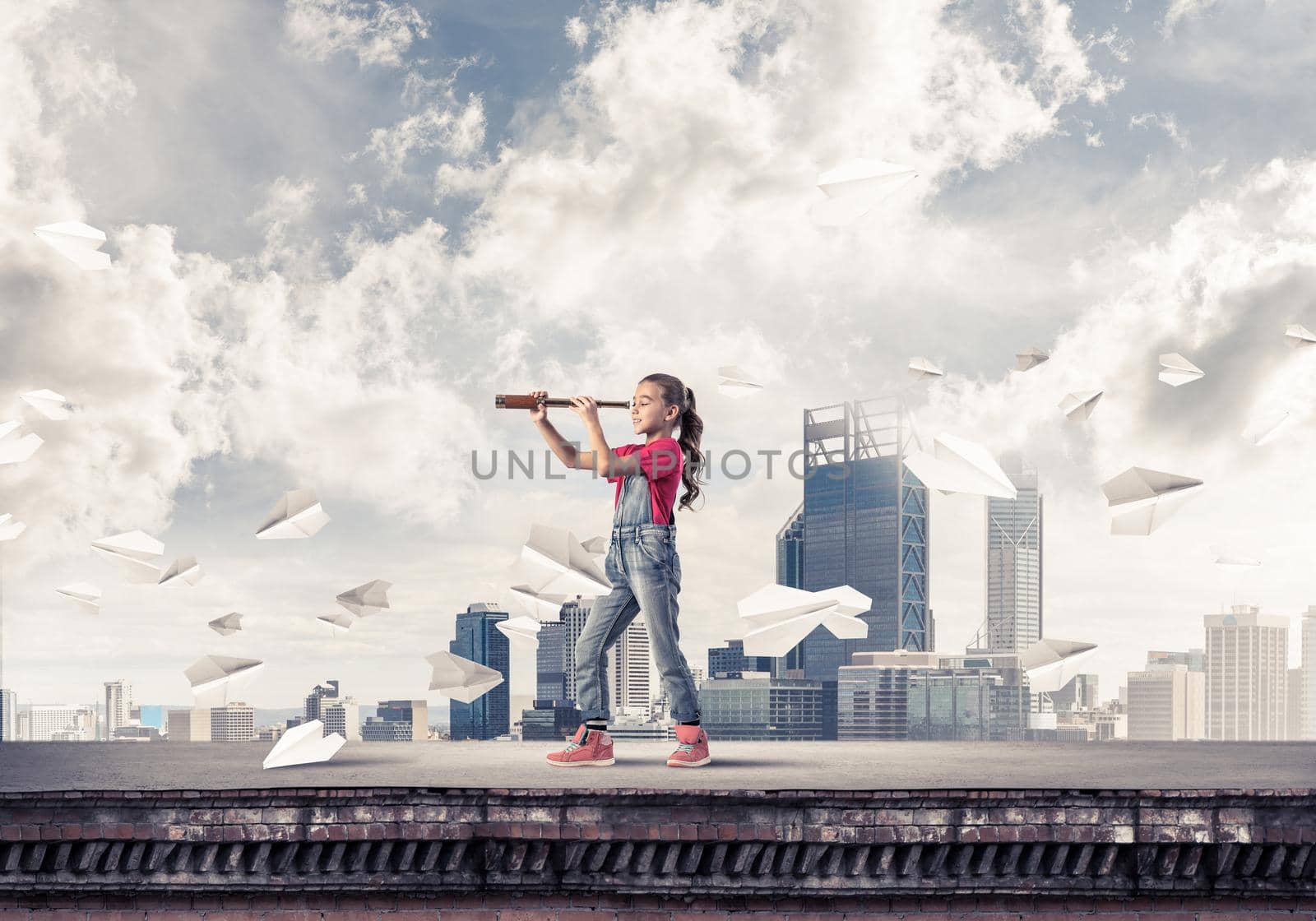 Cute kid girl standing on house roof and looking in spyglass