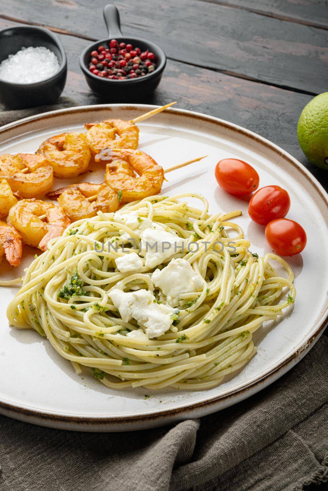 Italian pasta spaghetti with grilled shrimps, pesto sauce set, on plate, on old dark wooden table background