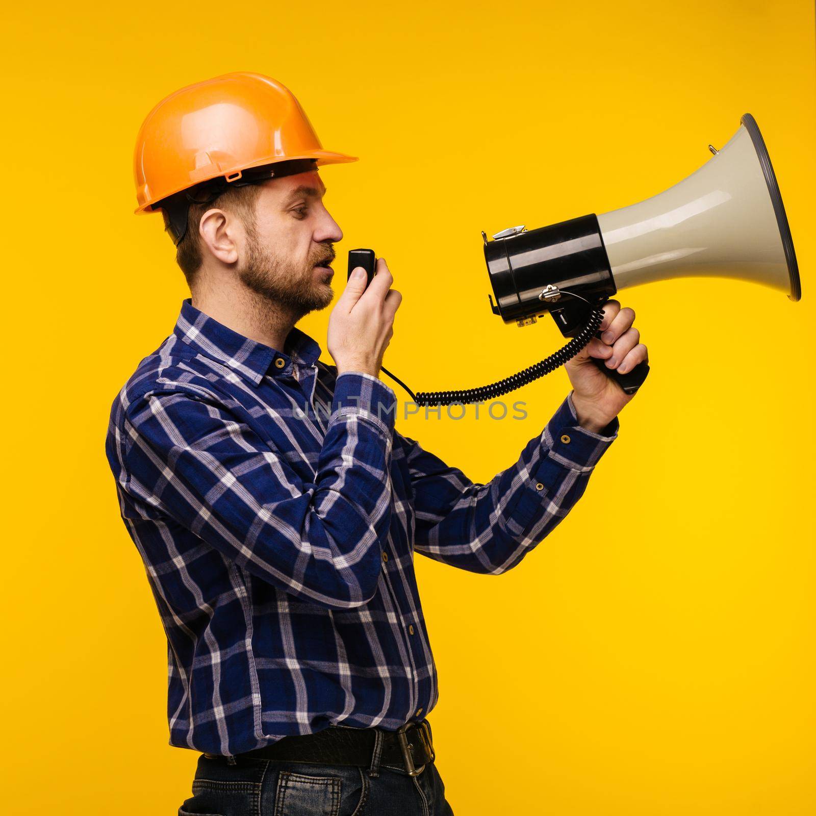 Angry worker man in orange helmet with a megaphone on yellow background - Image