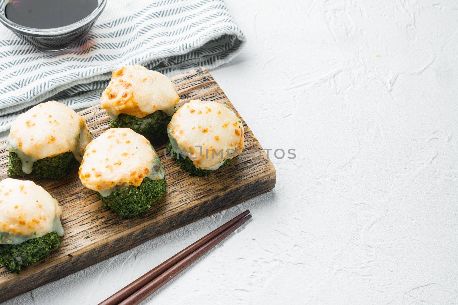 Baked sushi roll with shrimp and masago caviar cap. Traditional sushi restaurant dish set, on white stone background , with copyspace and space for text