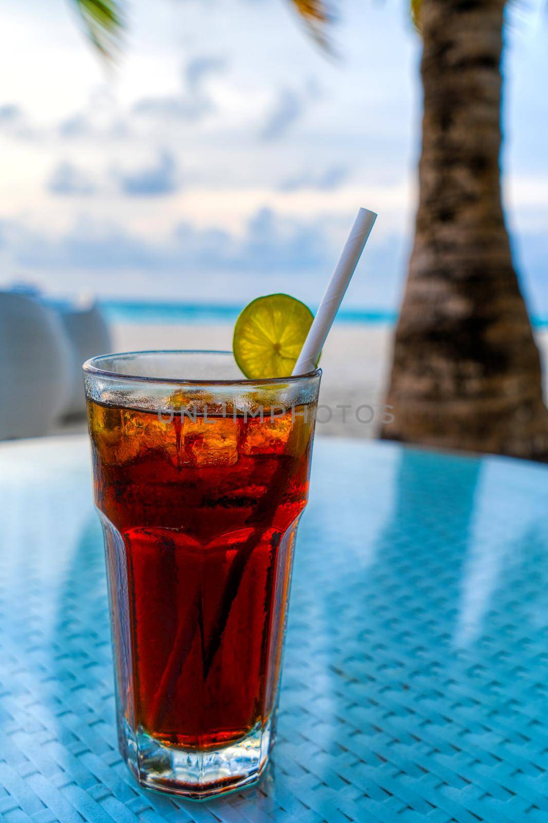 A glass of cold cocktail on a table on the beach in a restaurant by kolesnikov_studio